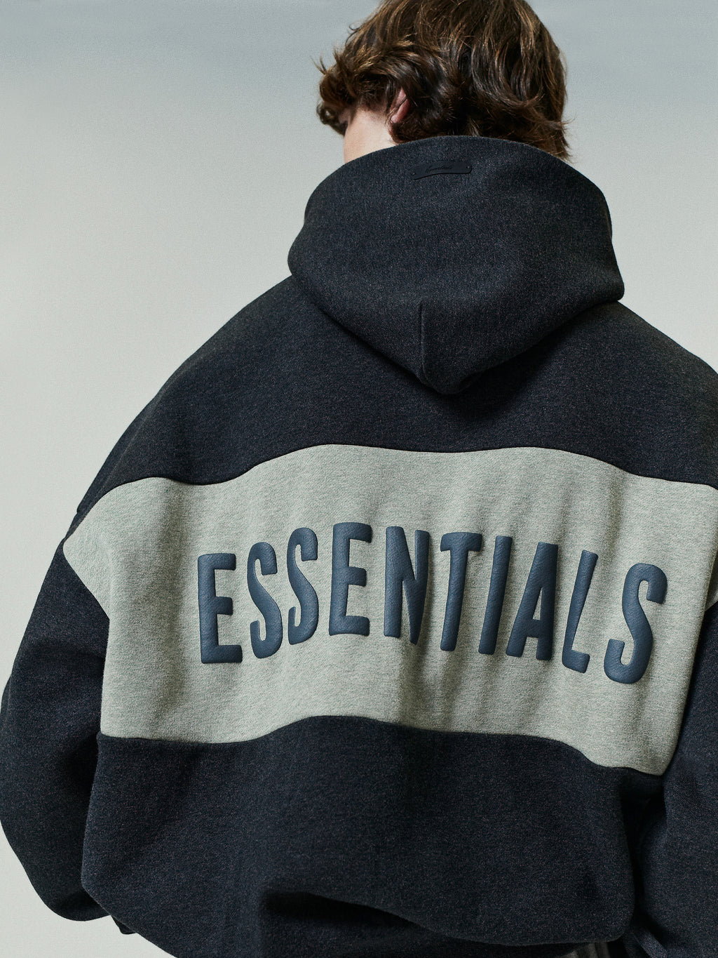 Cropped Relaxed Panelled Hoodie in a dark and light grey colorblock design, featuring a roomy hood and bold raised lettering across the back for a casual streetwear look.