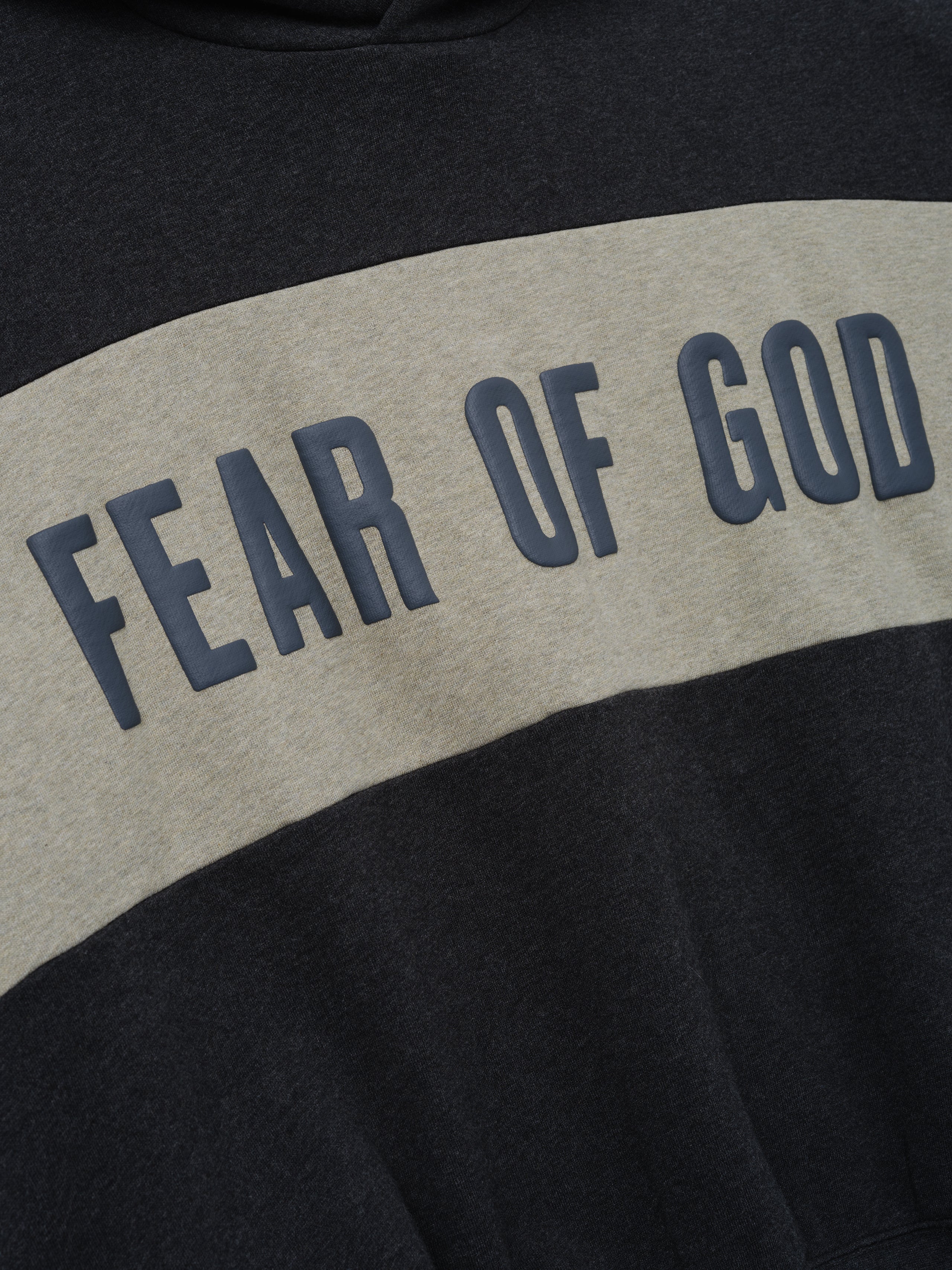 Cropped Relaxed Panelled Hoodie in dark iron grey with a wide contrasting panel across the chest featuring raised Fear of God lettering, designed for casual streetwear layering.