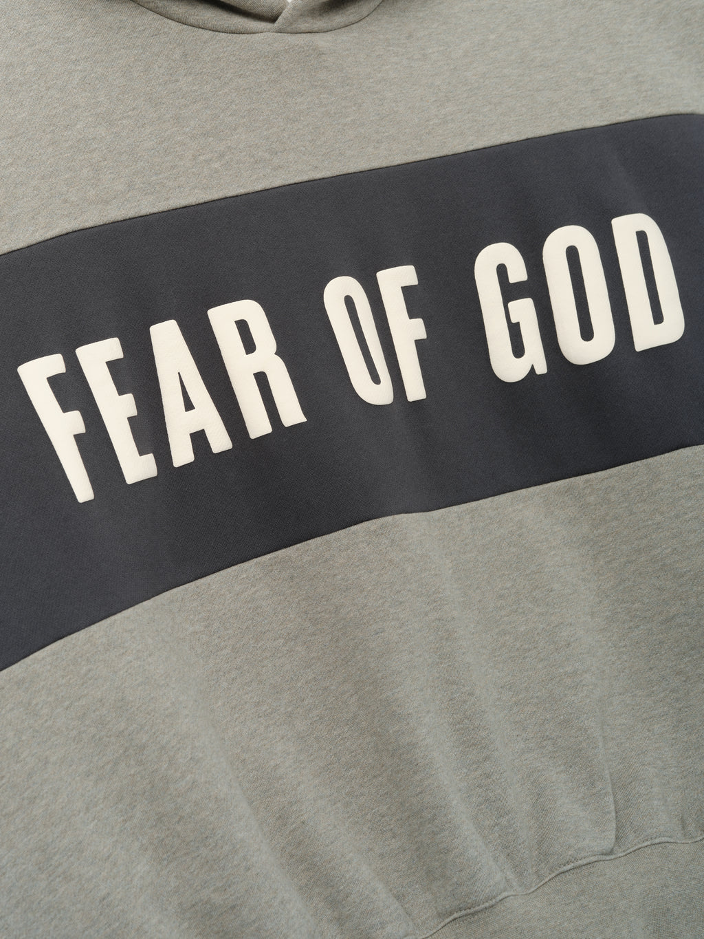 Cropped Relaxed Panelled Hoodie featuring a wide dark grey panel across the chest with bold cream "Fear of God" lettering, crafted for a modern, casual streetwear look.
