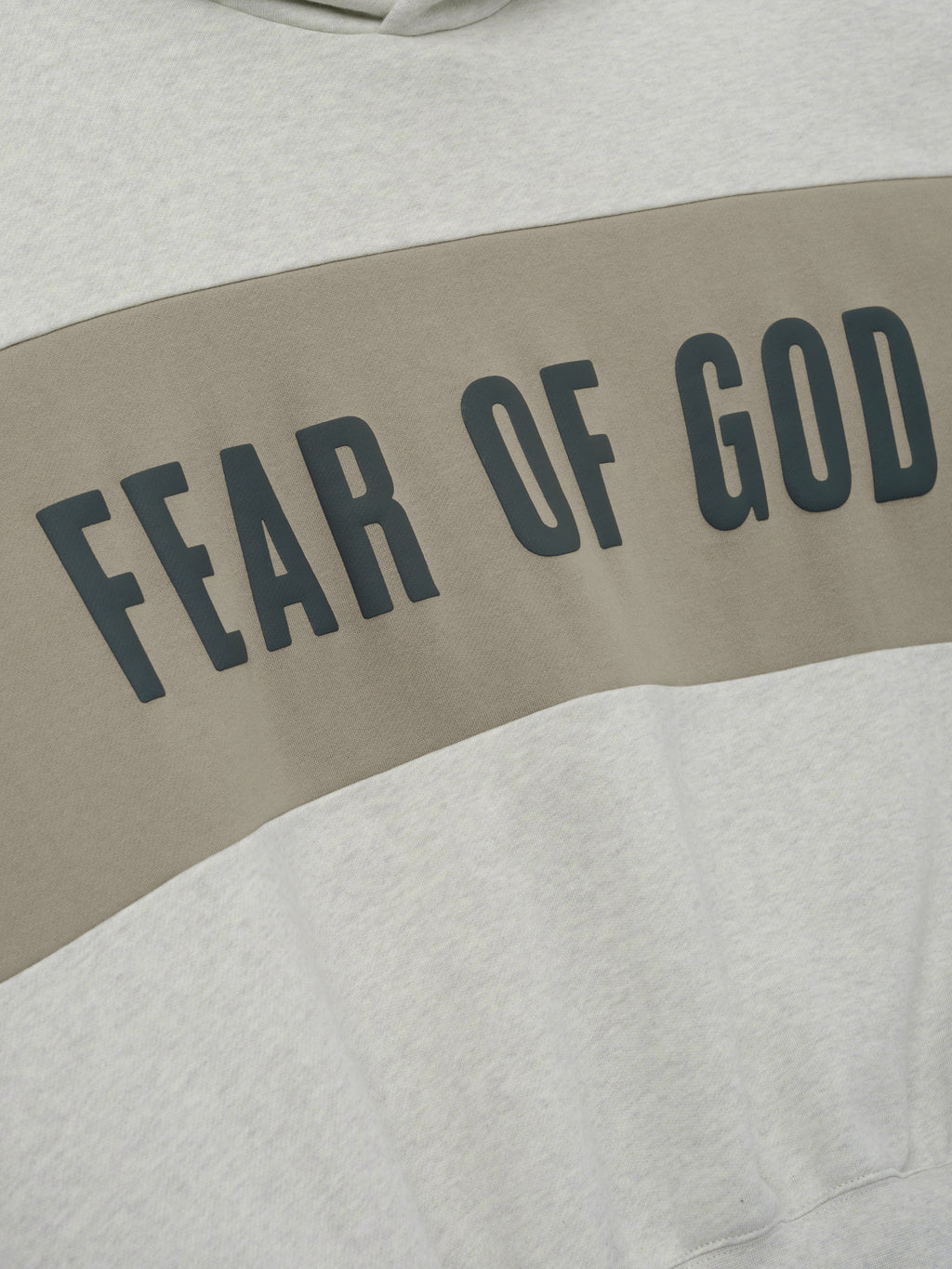 Cropped Relaxed Panelled Hoodie featuring a soft vanilla heather fabric with a wide muted taupe panel across the chest displaying bold black Fear of God lettering for a stylish streetwear look.