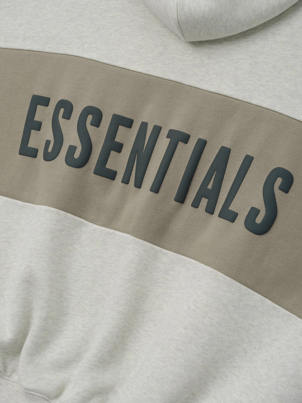 Cropped Relaxed Panelled Hoodie with a soft vanilla heather base and a wide muted taupe panel across the chest featuring raised black ESSENTIALS lettering for a modern streetwear look.
