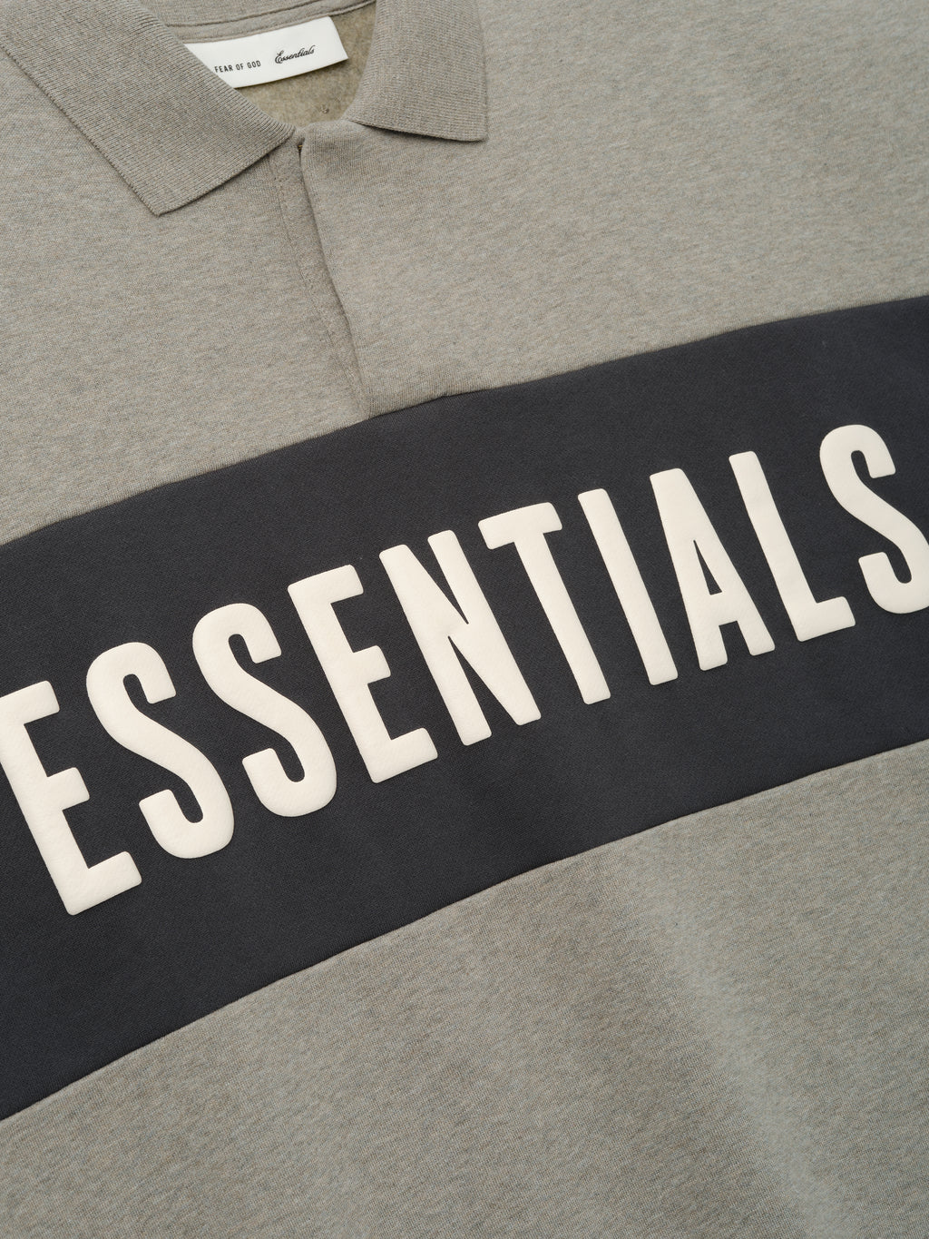 Cropped Panelled Polo featuring a muted grey tone with a contrasting dark horizontal panel and bold lettering, showcasing a classic collar and smooth fabric texture for casual tops.