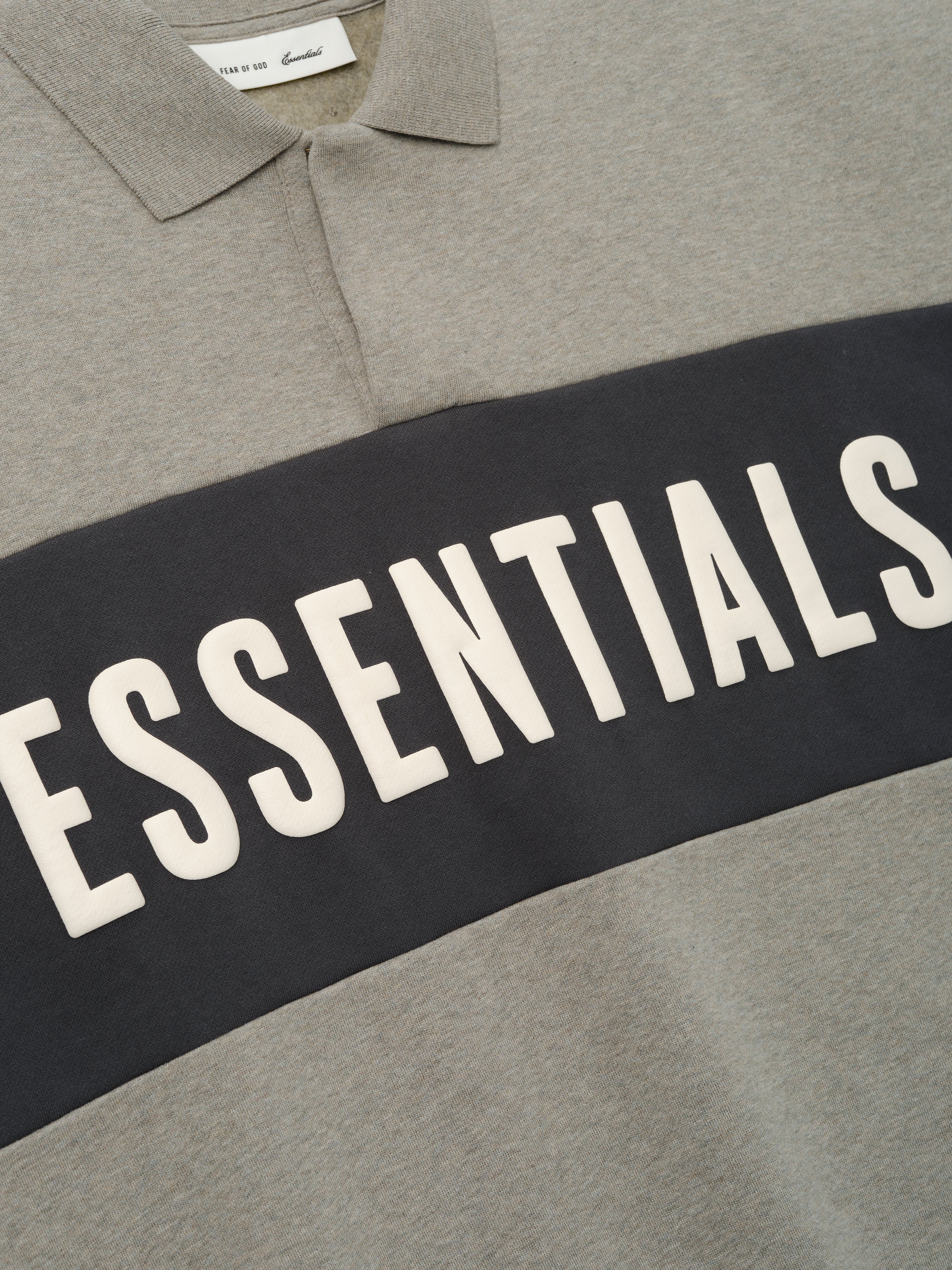 Cropped Panelled Polo featuring a muted grey tone with a contrasting dark horizontal panel and bold lettering, showcasing a classic collar and smooth fabric texture for casual tops.