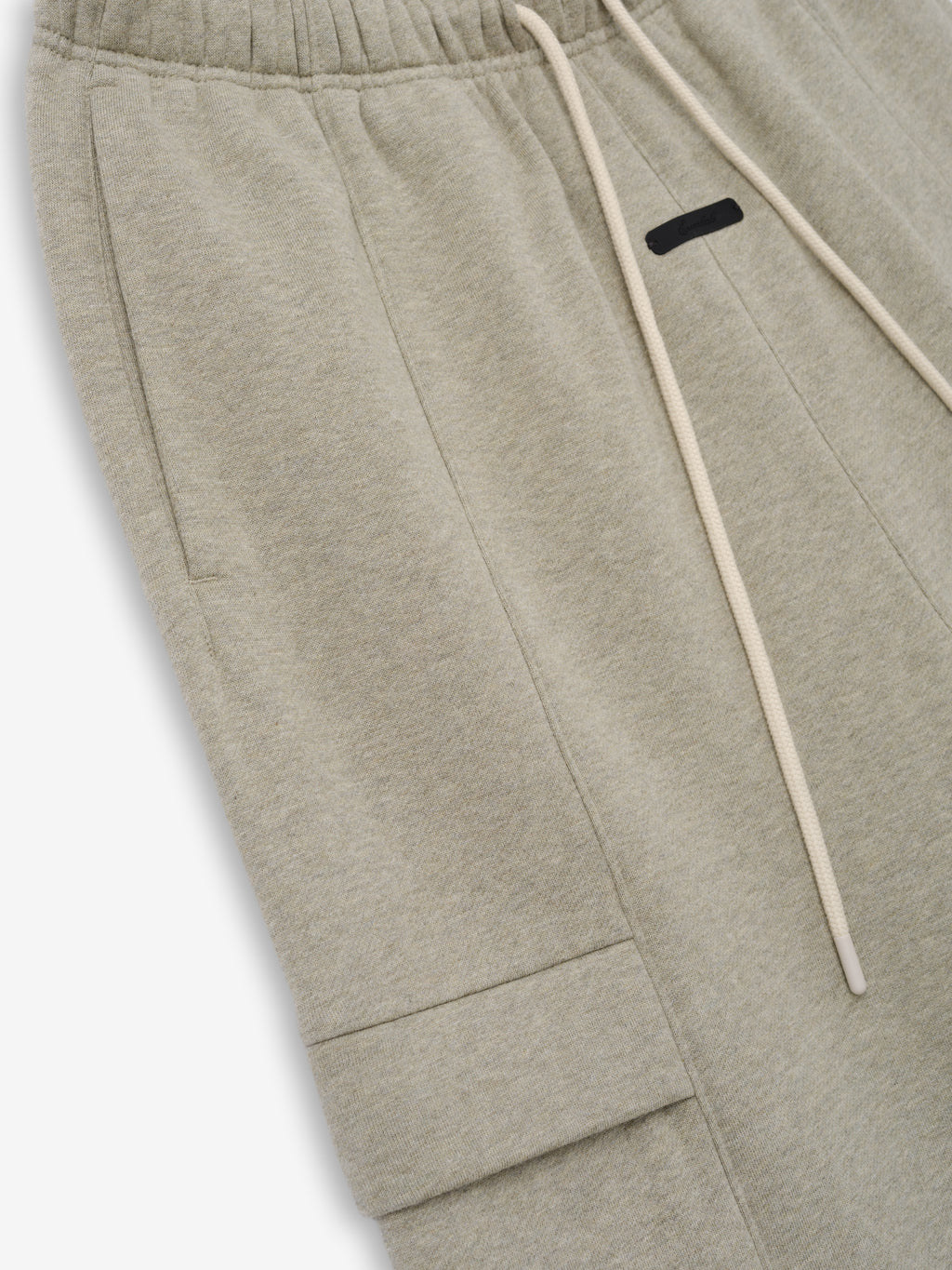 Fleece Cargo Field Pant in a soft heathered beige fabric with an elastic waistband, long beige drawstrings, side seam pockets, and a flap cargo pocket for practical, relaxed bottoms.