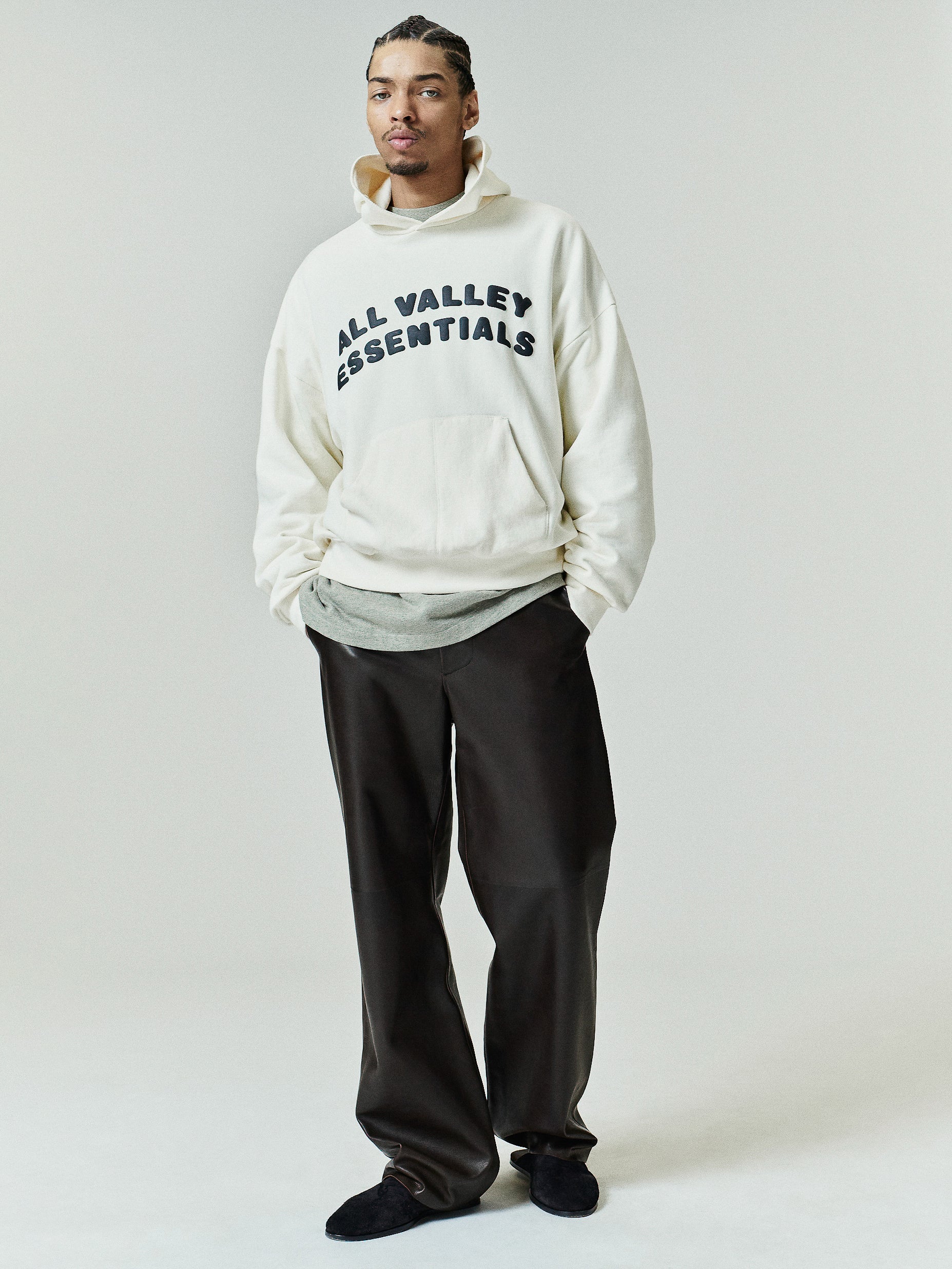 90s Hoodie in a soft washed ivory shade featuring bold black "ALL VALLEY ESSENTIALS" text on the chest, a roomy front kangaroo pocket, and a relaxed fit with dropped shoulders.