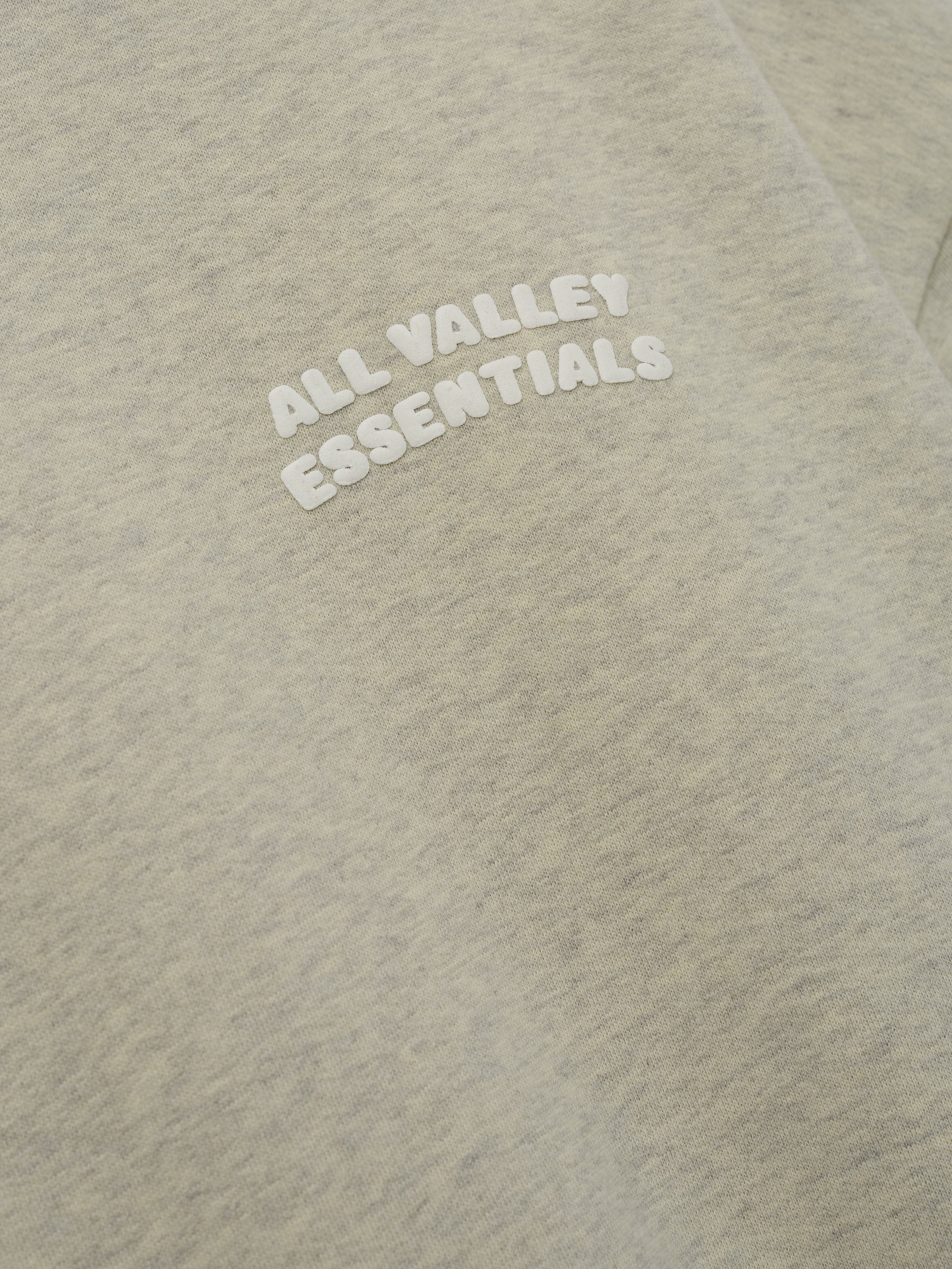 90s Sweatshirt in a soft washed vanilla heather shade featuring a cozy fabric texture with a small white embossed "ALL VALLEY ESSENTIALS" text on the chest for casual tops.