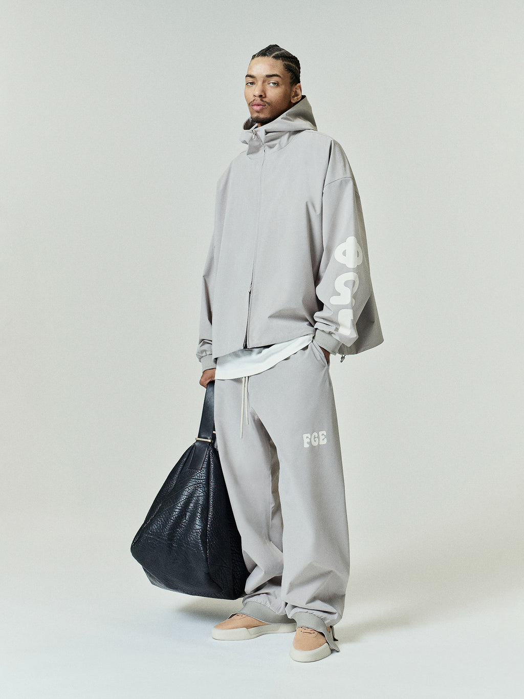 Full Zip Hooded Anorak in a light muted tone featuring an oversized fit with a high neckline and bold graphic lettering on the sleeve for contemporary outerwear style.