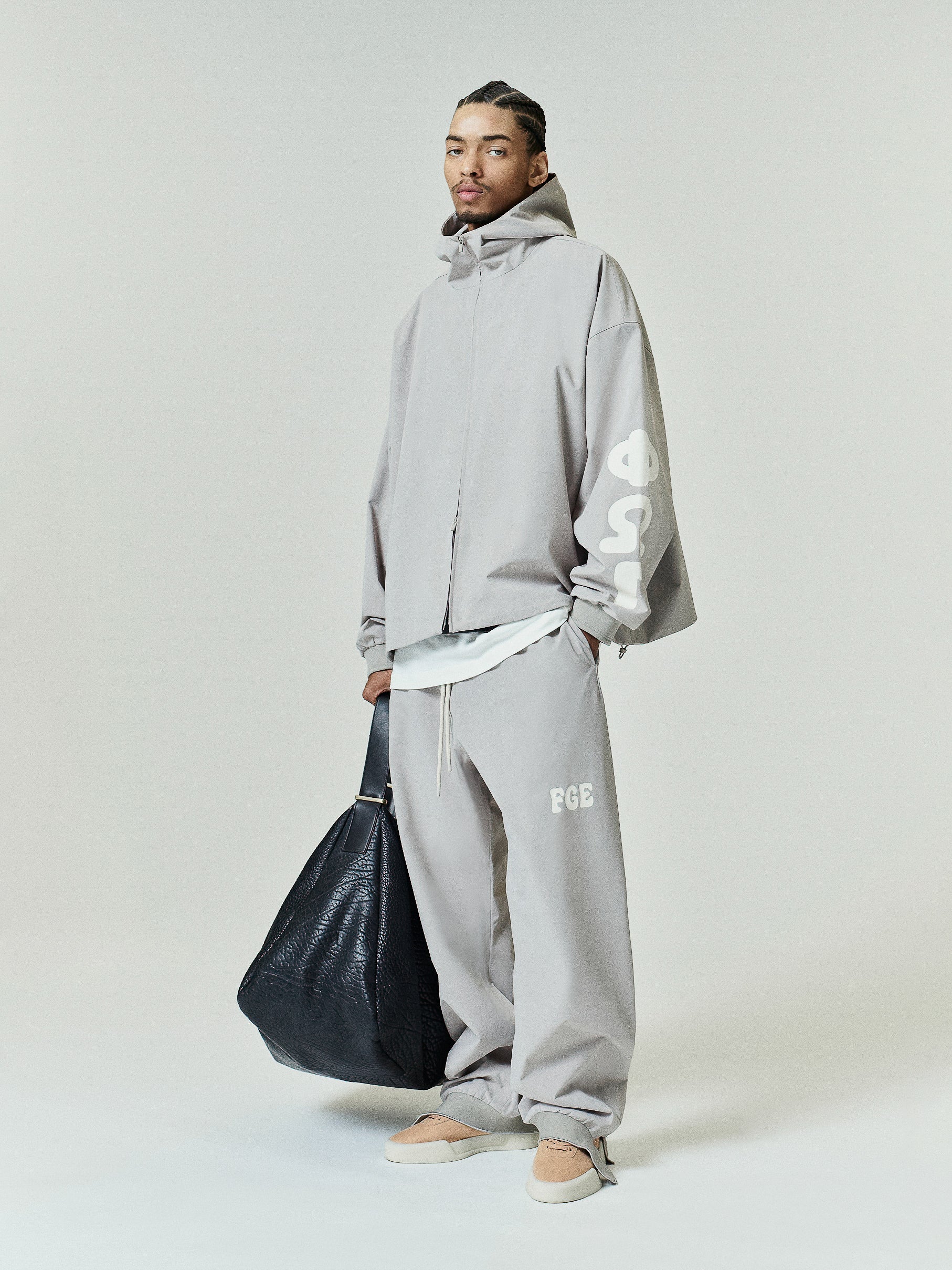 Full Zip Hooded Anorak in a light muted tone featuring an oversized fit with a high neckline and bold graphic lettering on the sleeve for contemporary outerwear style.