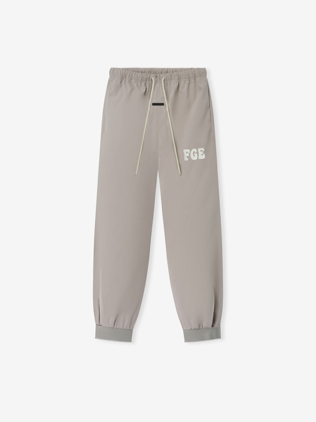 Storm Pant in a muted neutral tone featuring elastic waistband with long drawstrings, subtle embroidered logo detail on the thigh, and cuffed ankles for a tailored yet comfortable fit.