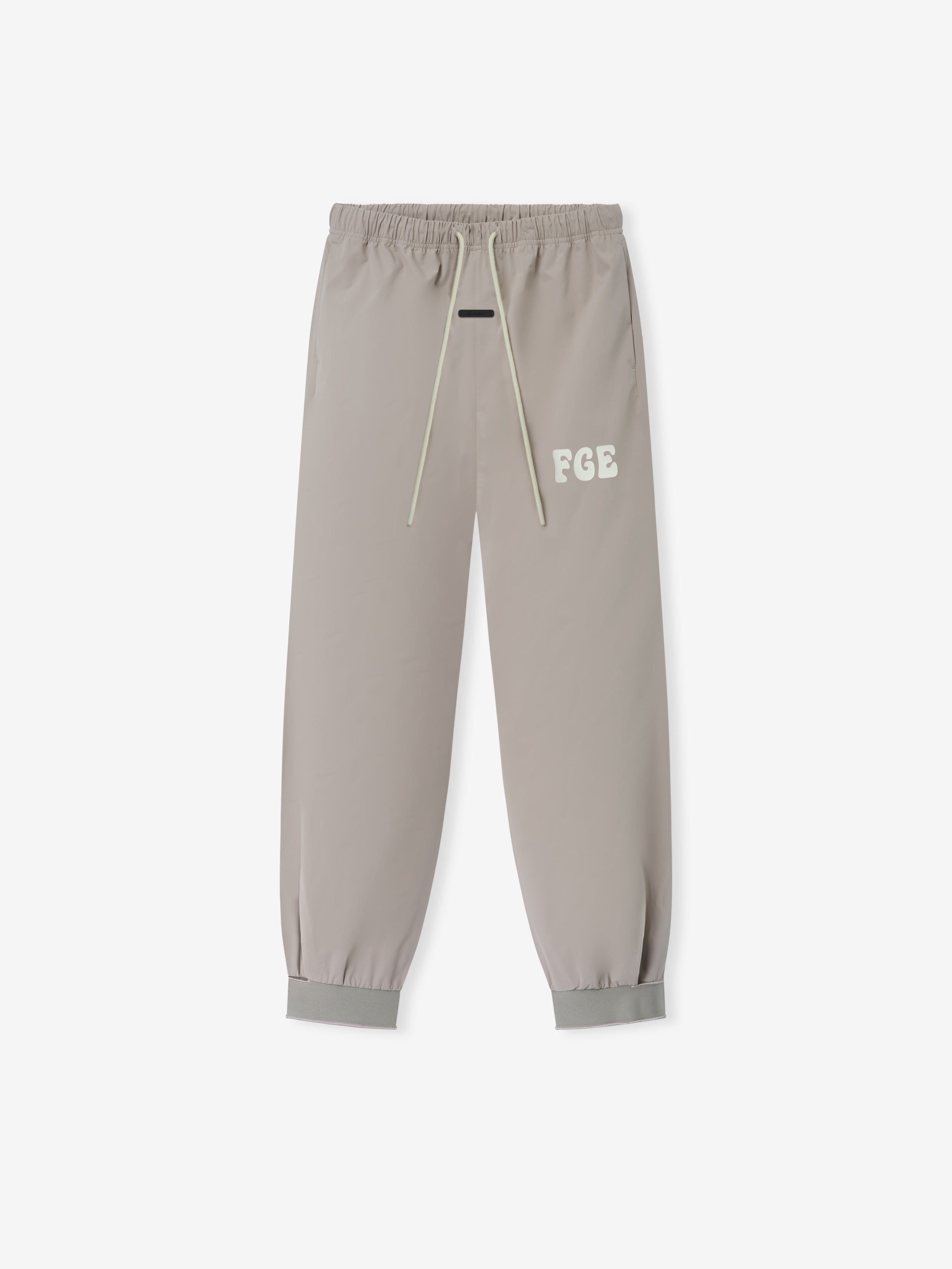 Storm Pant in a muted neutral tone featuring elastic waistband with long drawstrings, subtle embroidered logo detail on the thigh, and cuffed ankles for a tailored yet comfortable fit.