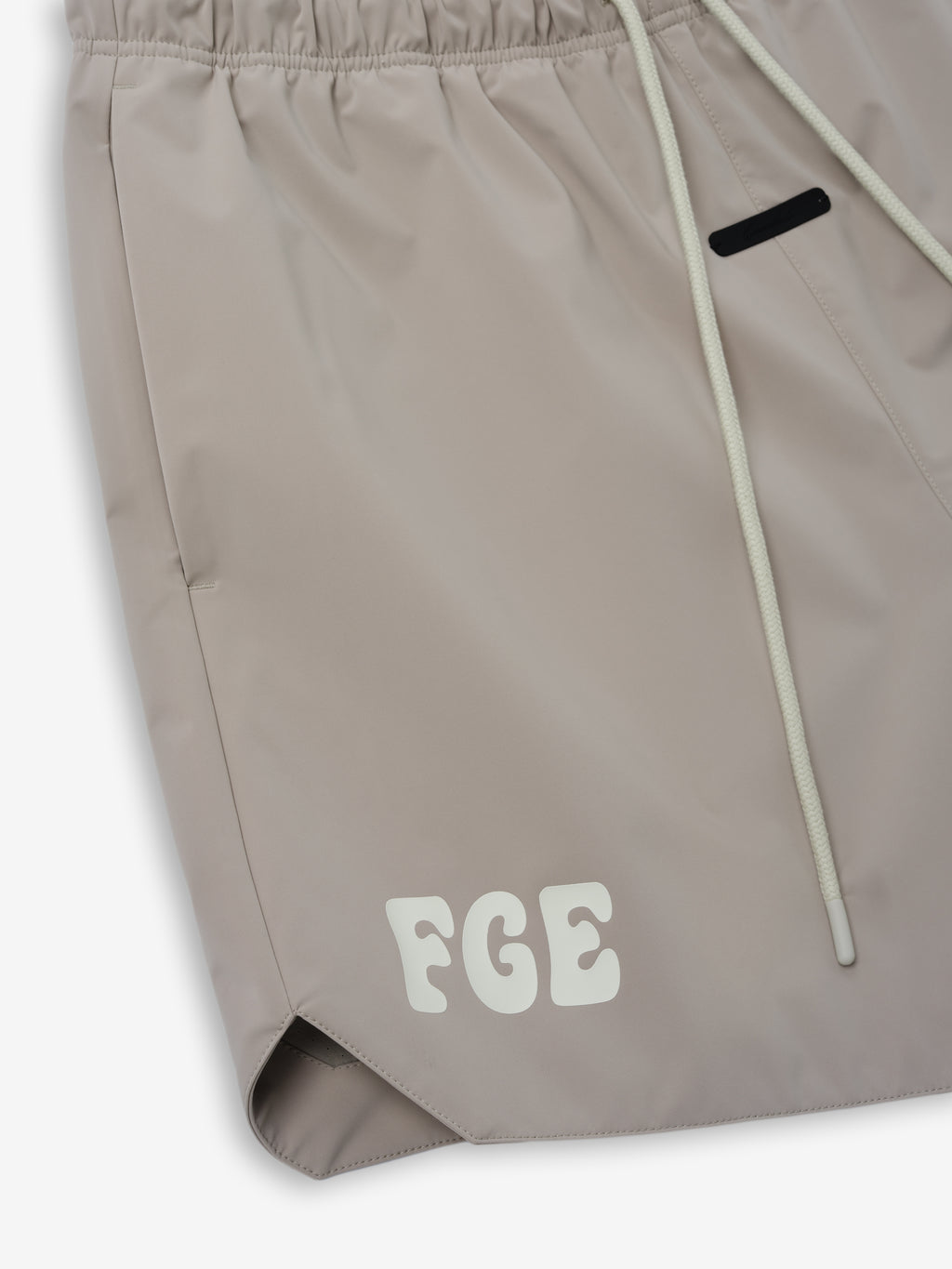 Gym Short in a soft neutral tone featuring an elastic waistband with drawstrings, side pockets, and subtle branding detailing for a modern and comfortable bottoms choice.