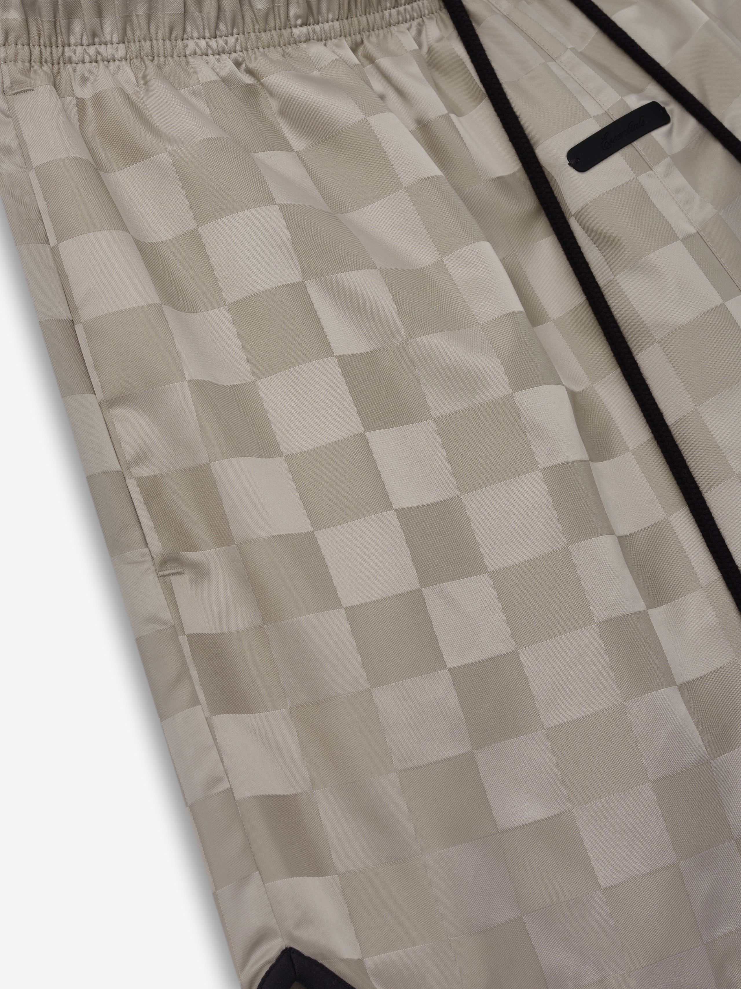 Nylon Checkered Gym Short in a muted beige shade with a subtle checkered pattern, featuring an elastic waistband and black drawstrings for adjustable fit and sporty style.