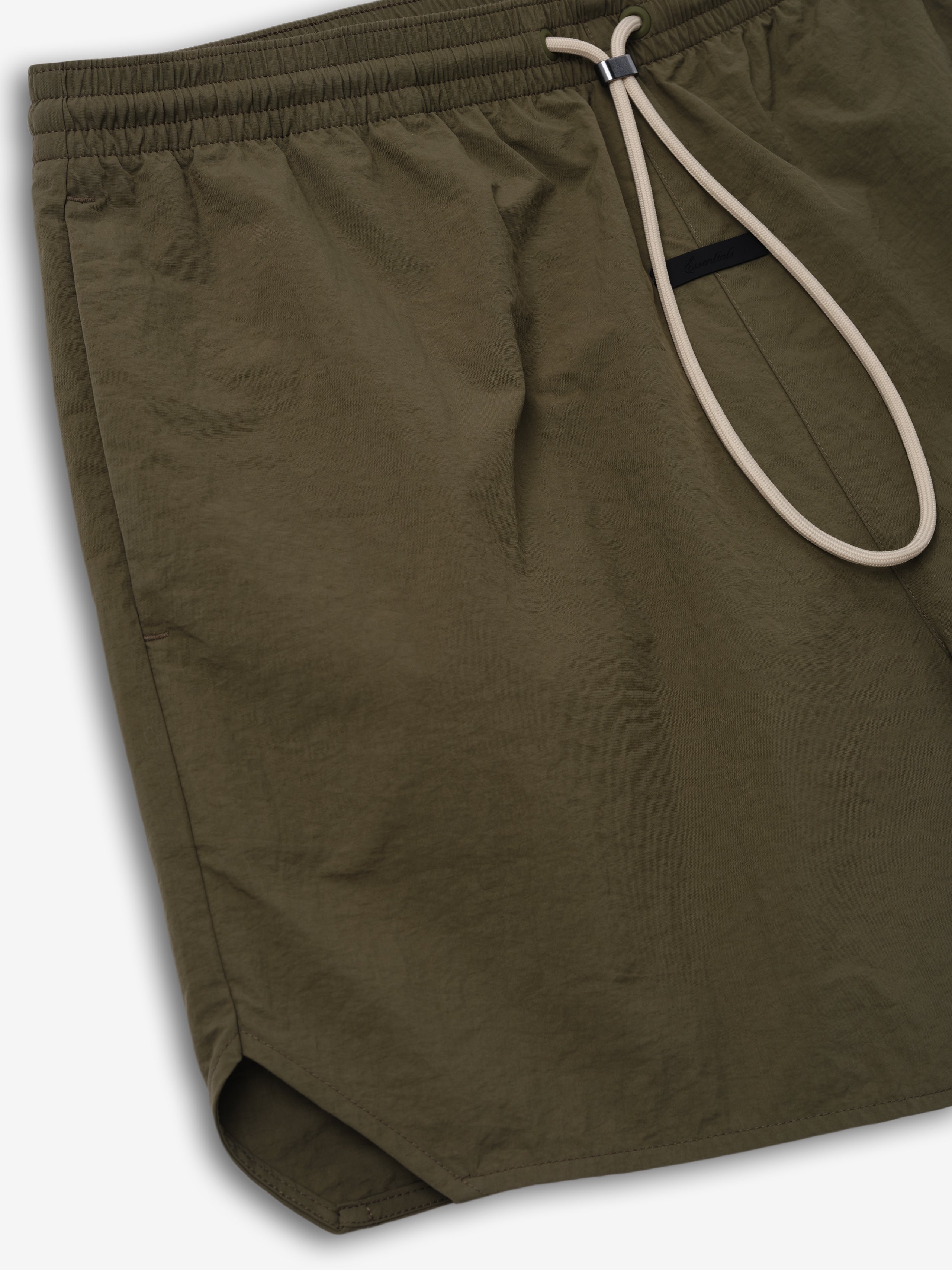 Nylon Swim Short in a deep moss green shade with a relaxed fit, featuring an elastic waistband and beige drawstrings for adjustable comfort and subtle sporty detailing.