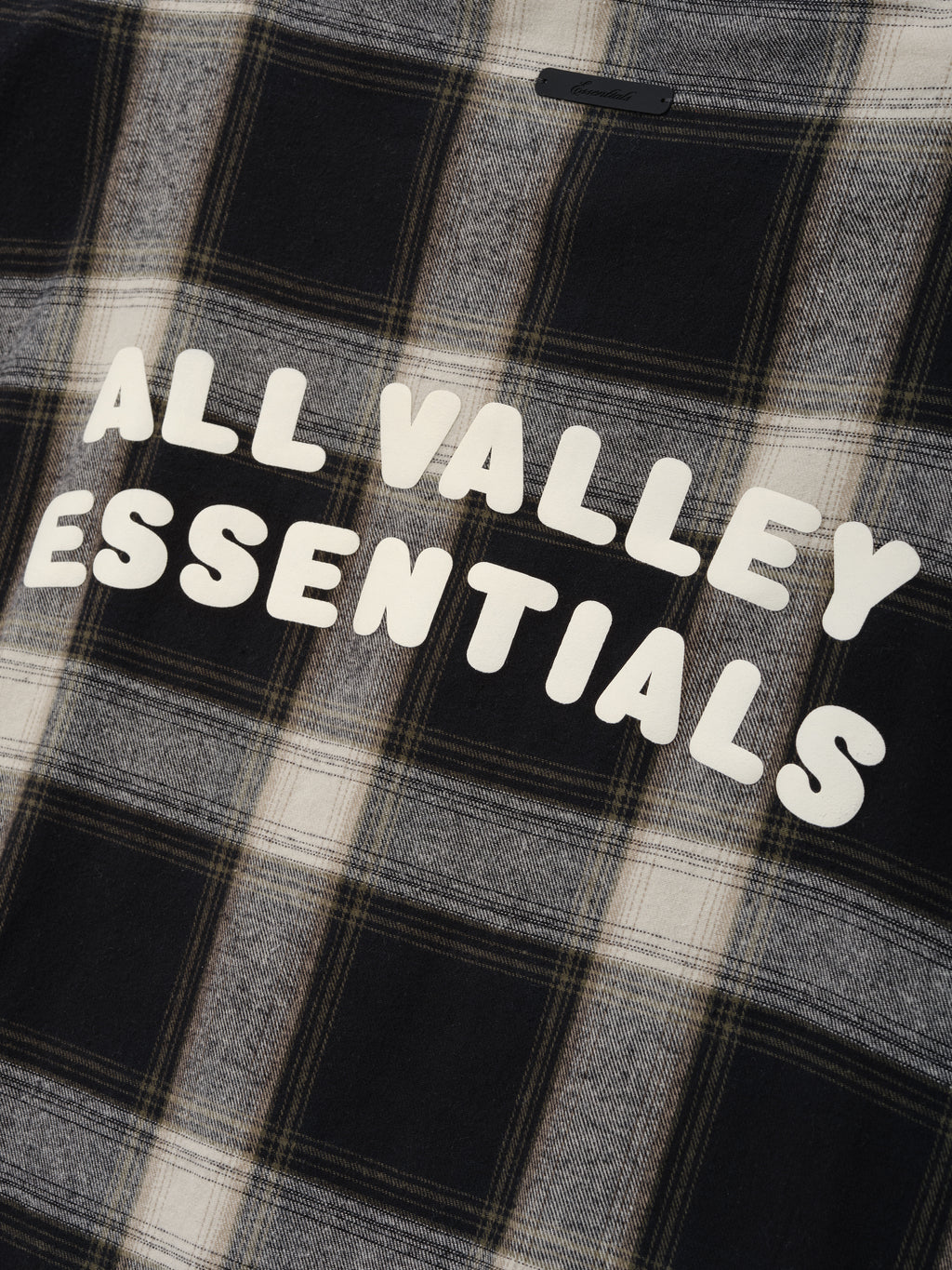 Flannel Button Up Shirt in muted grey and black plaid pattern with soft fabric and bold white text graphic reading "ALL VALLEY ESSENTIALS" across the back for casual tops.