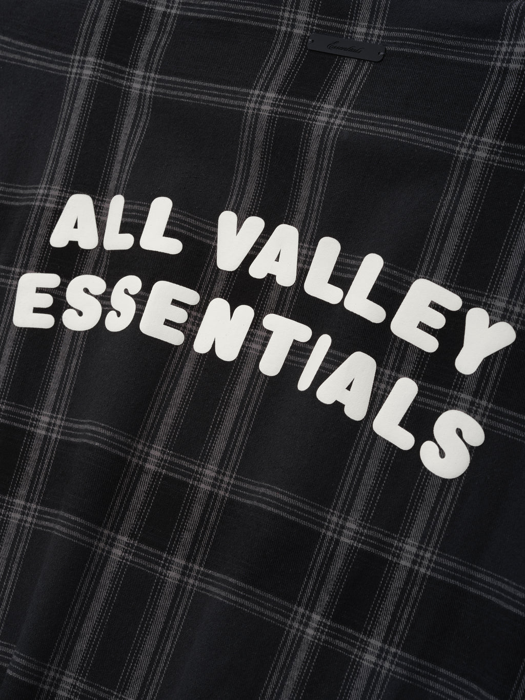Flannel Button Up Shirt in vintage black plaid pattern featuring a soft woven fabric with bold white lettering "ALL VALLEY ESSENTIALS" printed across the back for casual tops.