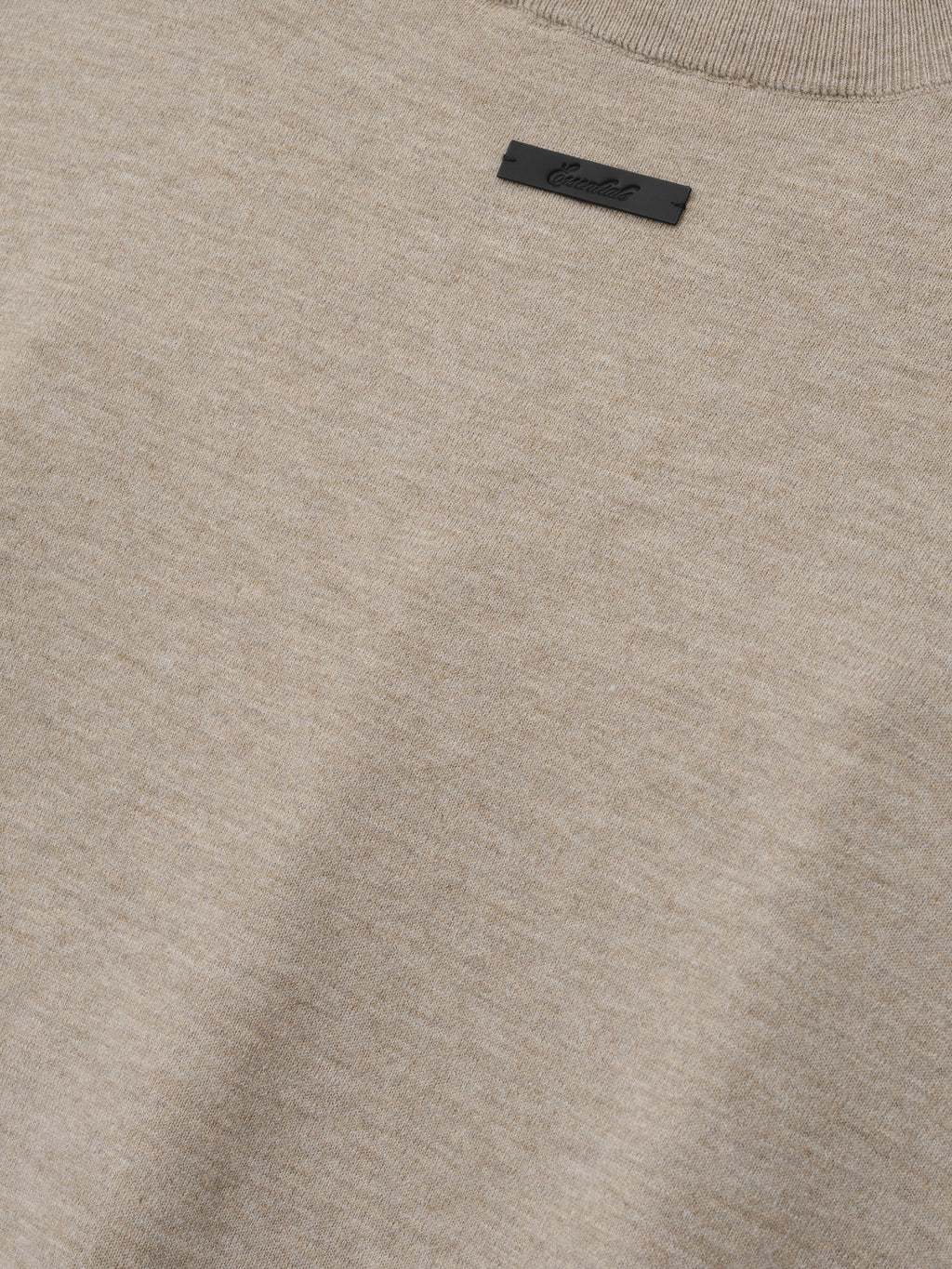 Soft Knit Tee in a soft, neutral beige heather shade, featuring a finely woven knit texture with a subtle ribbed neckline and a small black logo tag for understated style.