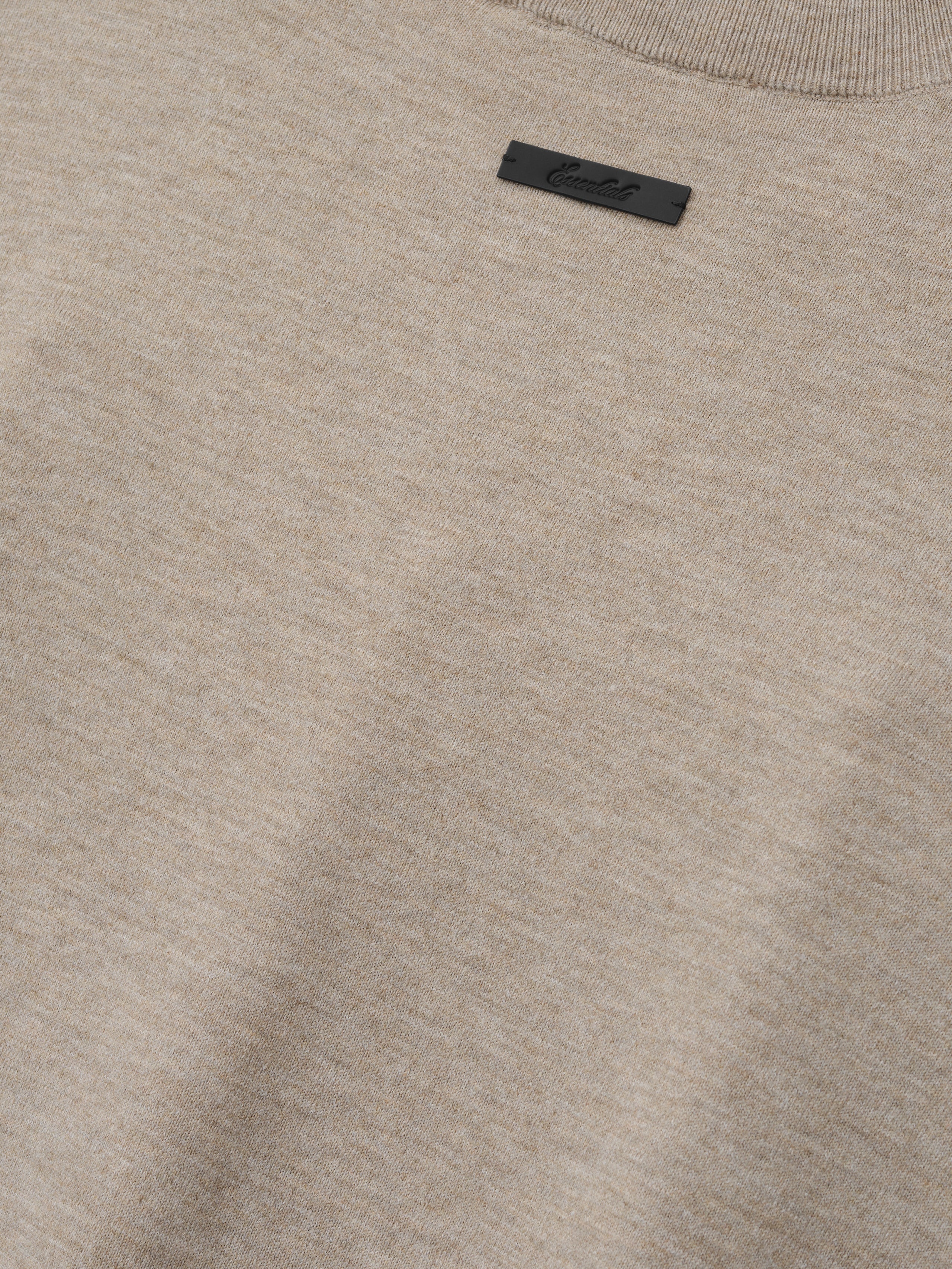 Soft Knit Tee in a soft, neutral beige heather shade, featuring a finely woven knit texture with a subtle ribbed neckline and a small black logo tag for understated style.