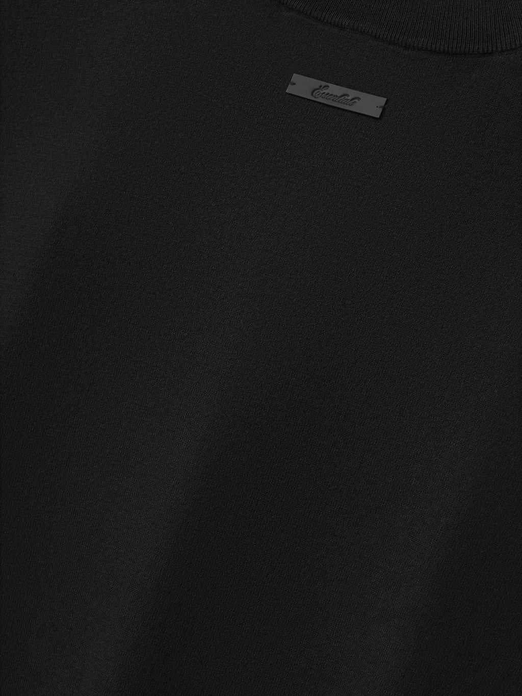 Soft Knit Tee in a rich black shade, showcasing a smooth knit texture with a subtle ribbed neckline and a small tonal logo tag for minimalist, modern tops.