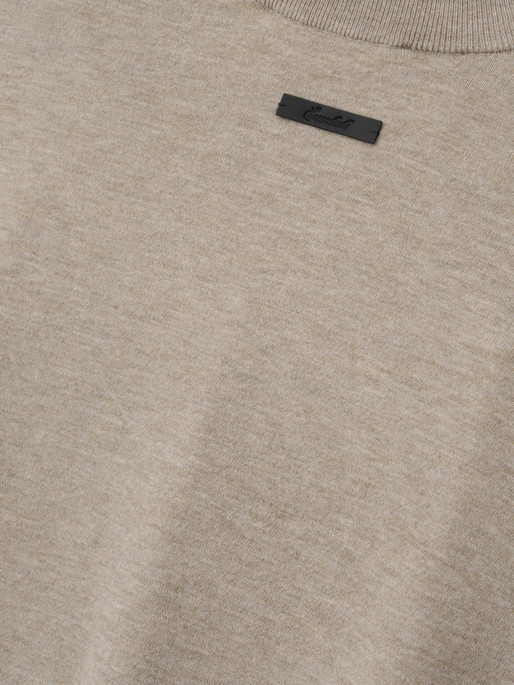 Soft Knit Long Sleeve Tee in a light neutral tone with a finely woven knit texture, featuring a subtle ribbed neckline and a small, understated black brand tag for minimalist style.