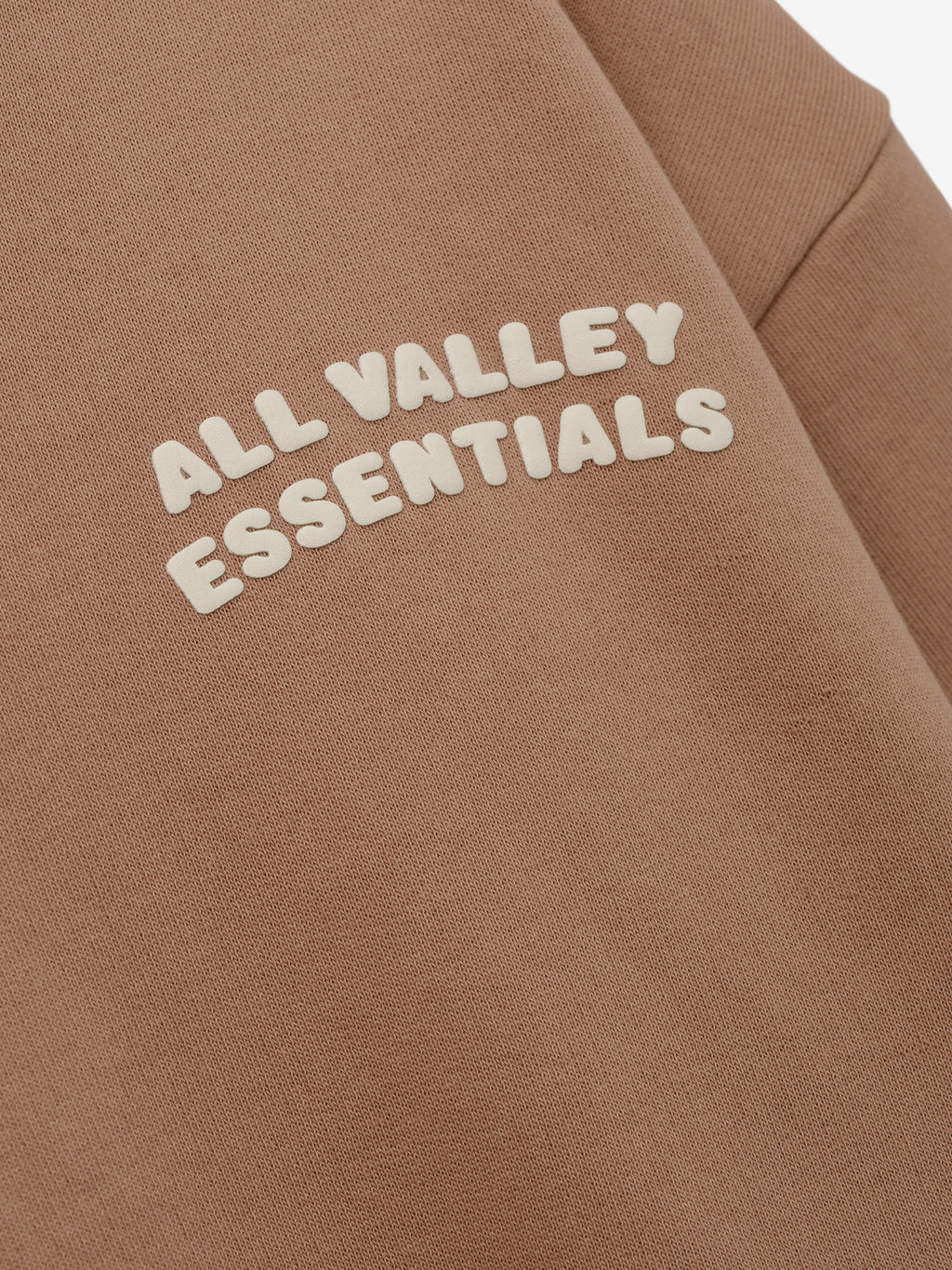 Womens 90s Full Zip Hoodie in a warm ginger tone featuring close-up detail of raised cream lettering on soft fabric for a cozy and stylish outerwear look.