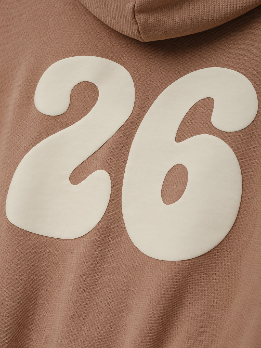 Womens 90s Full Zip Hoodie in a muted ginger shade featuring a close-up of large cream-colored “26” graphic on soft fabric, highlighting vintage-inspired outerwear detail.