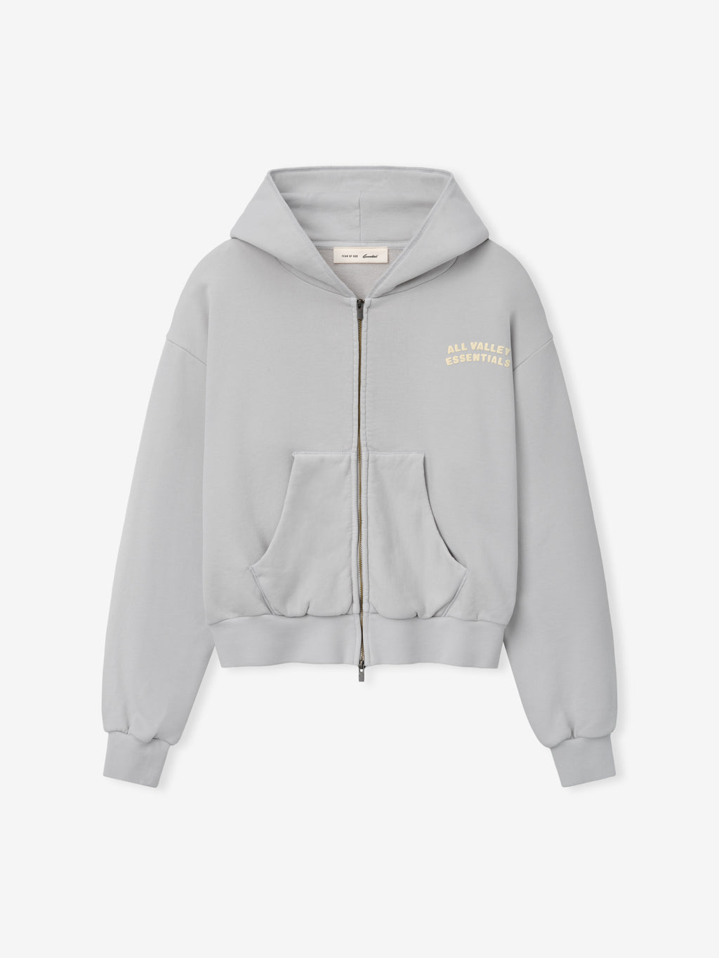 90s Full Zip Hoodie in a soft light gray with a full front zipper, split kangaroo pockets, ribbed cuffs, and subtle cream text on the chest for a minimalist outerwear style.