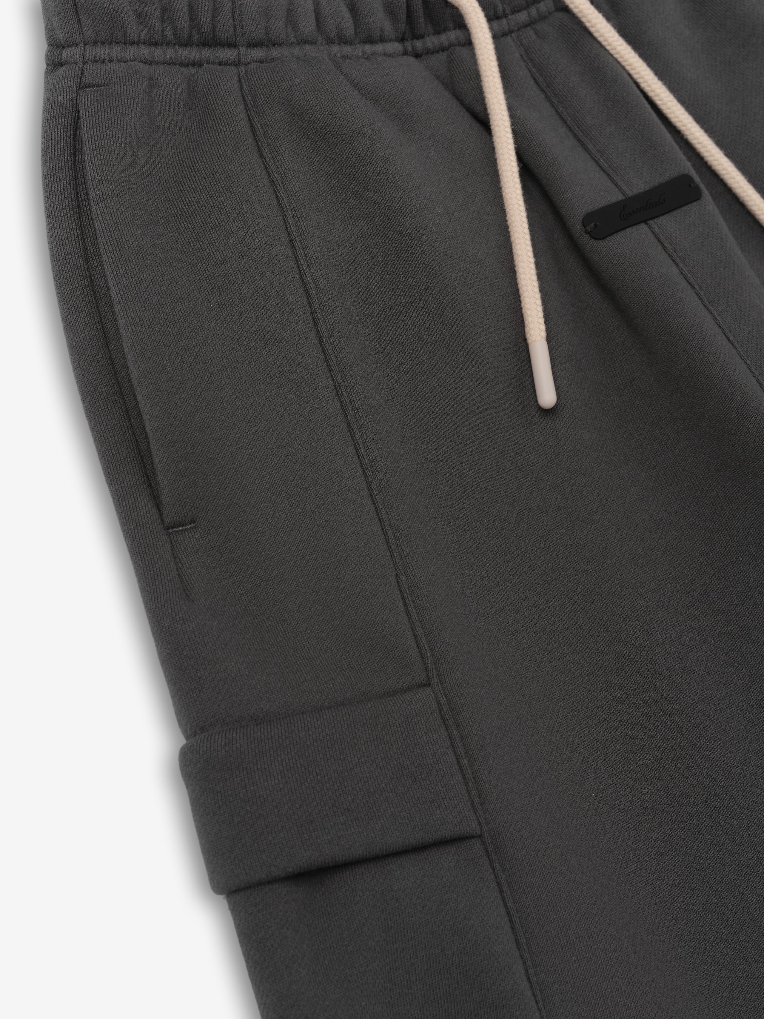 Kids Fleece Cargo Basketball Short in a deep grey tone, featuring an elastic waistband with beige drawstrings, side pockets, and a flap cargo pocket for functional and cozy kids' bottoms.