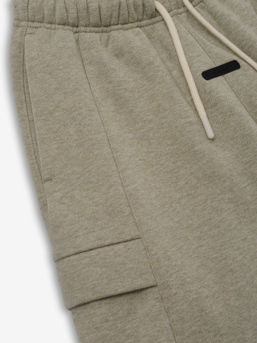 Kids Fleece Cargo Basketball Short in a muted beige-green shade, featuring a soft elastic waistband with drawstrings and a functional side cargo pocket for comfortable kids bottoms.