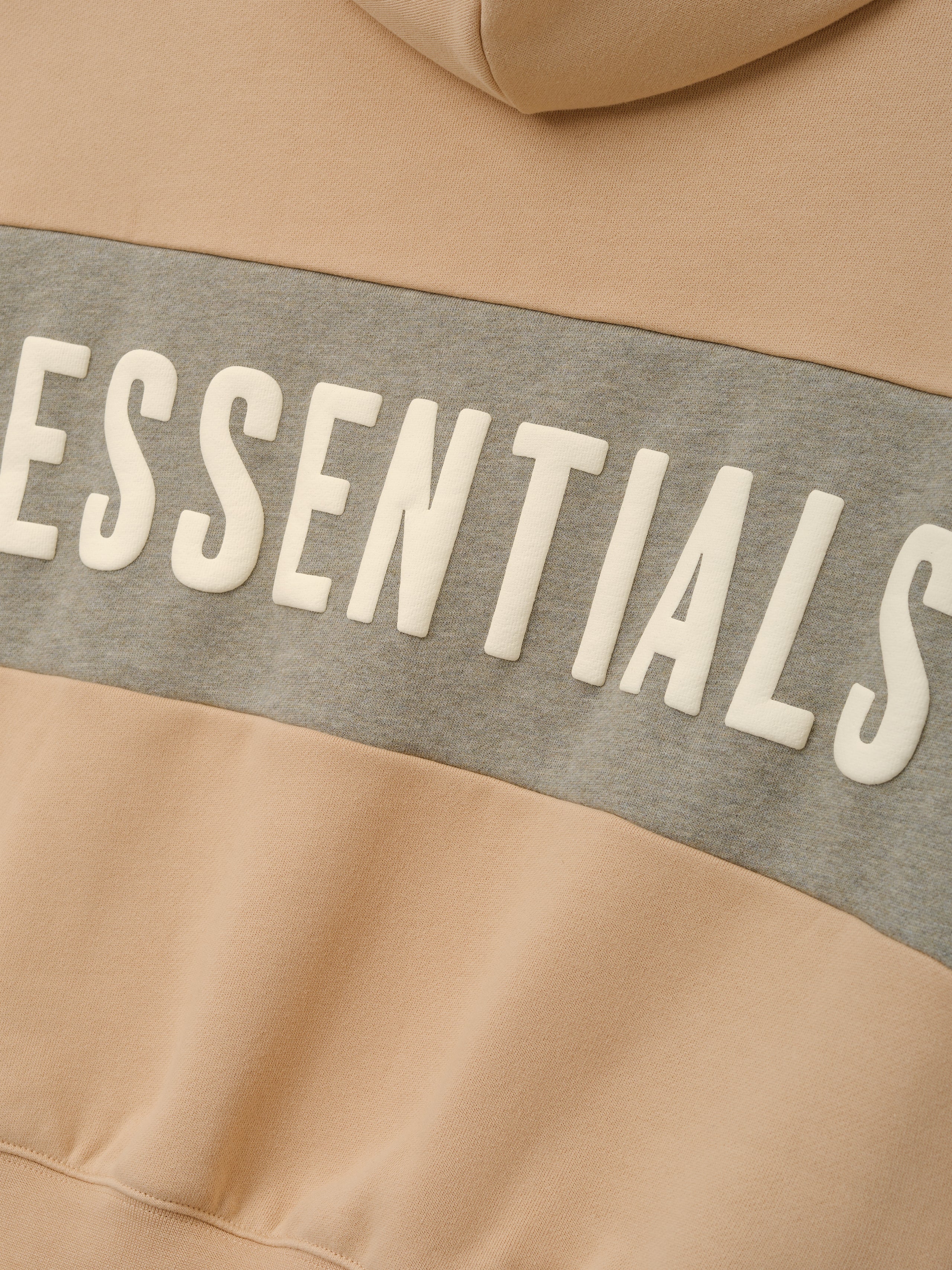 Kids Cropped Relaxed Panelled Hoodie in a soft beige with a contrasting grey panel across the chest featuring raised "ESSENTIALS" lettering for trendy kids outerwear.