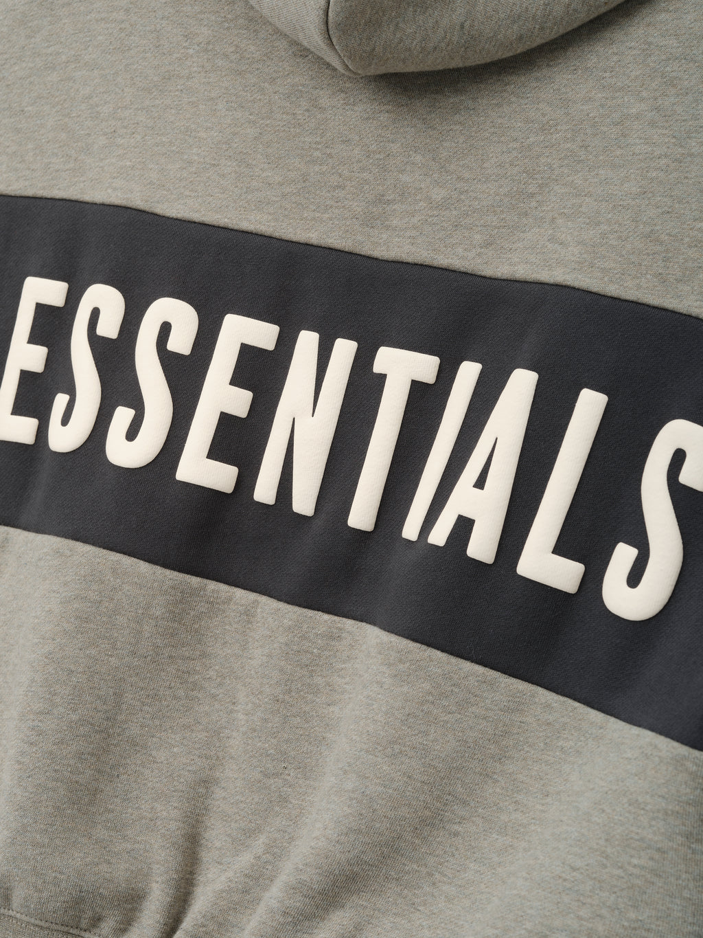 Kids Cropped Relaxed Panelled Hoodie in a muted grey fabric with a contrasting dark panel across the chest featuring raised "ESSENTIALS" lettering for a stylish kids outerwear piece.