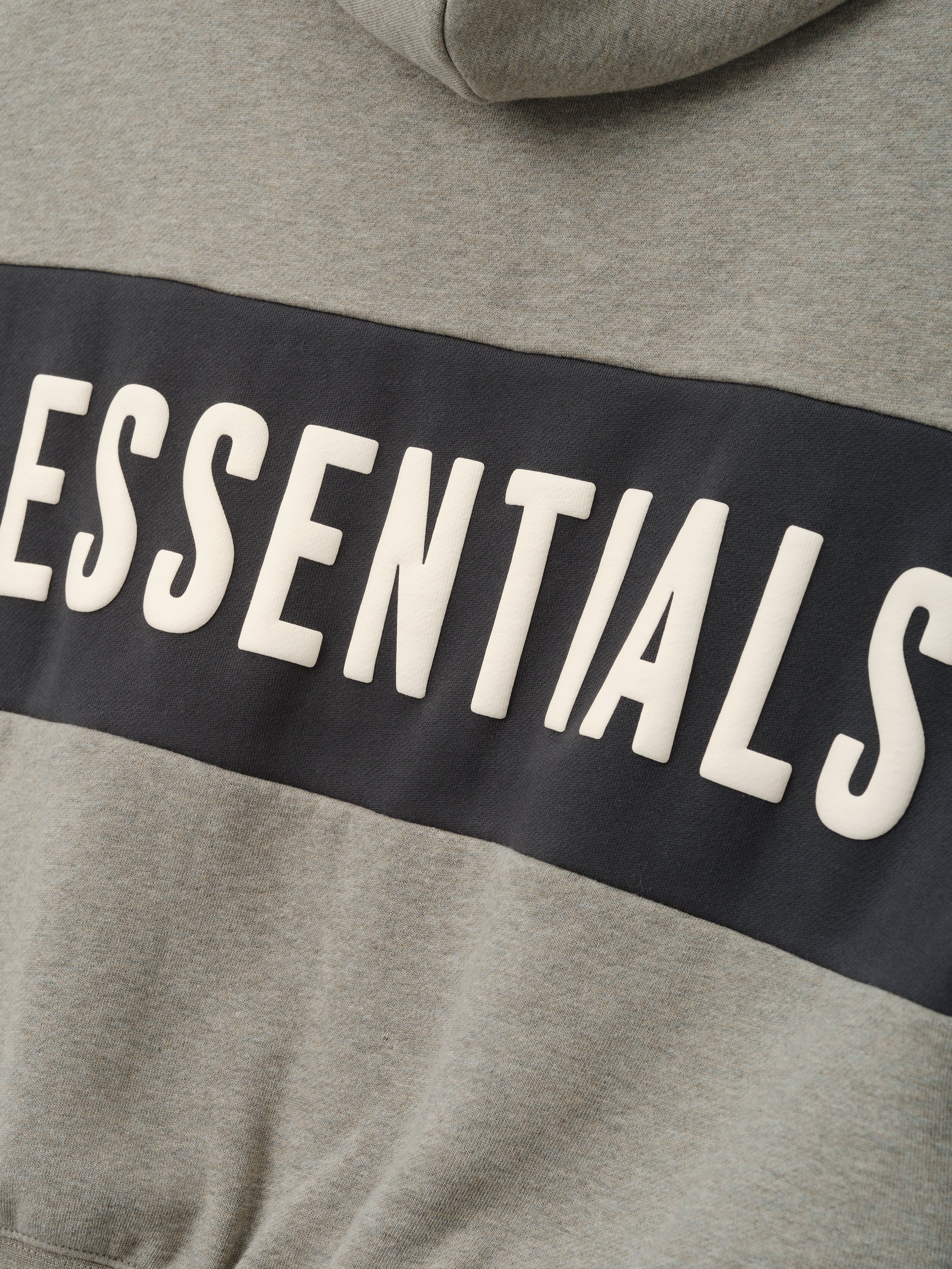 Kids Cropped Relaxed Panelled Hoodie in a muted grey fabric with a contrasting dark panel across the chest featuring raised "ESSENTIALS" lettering for a stylish kids outerwear piece.