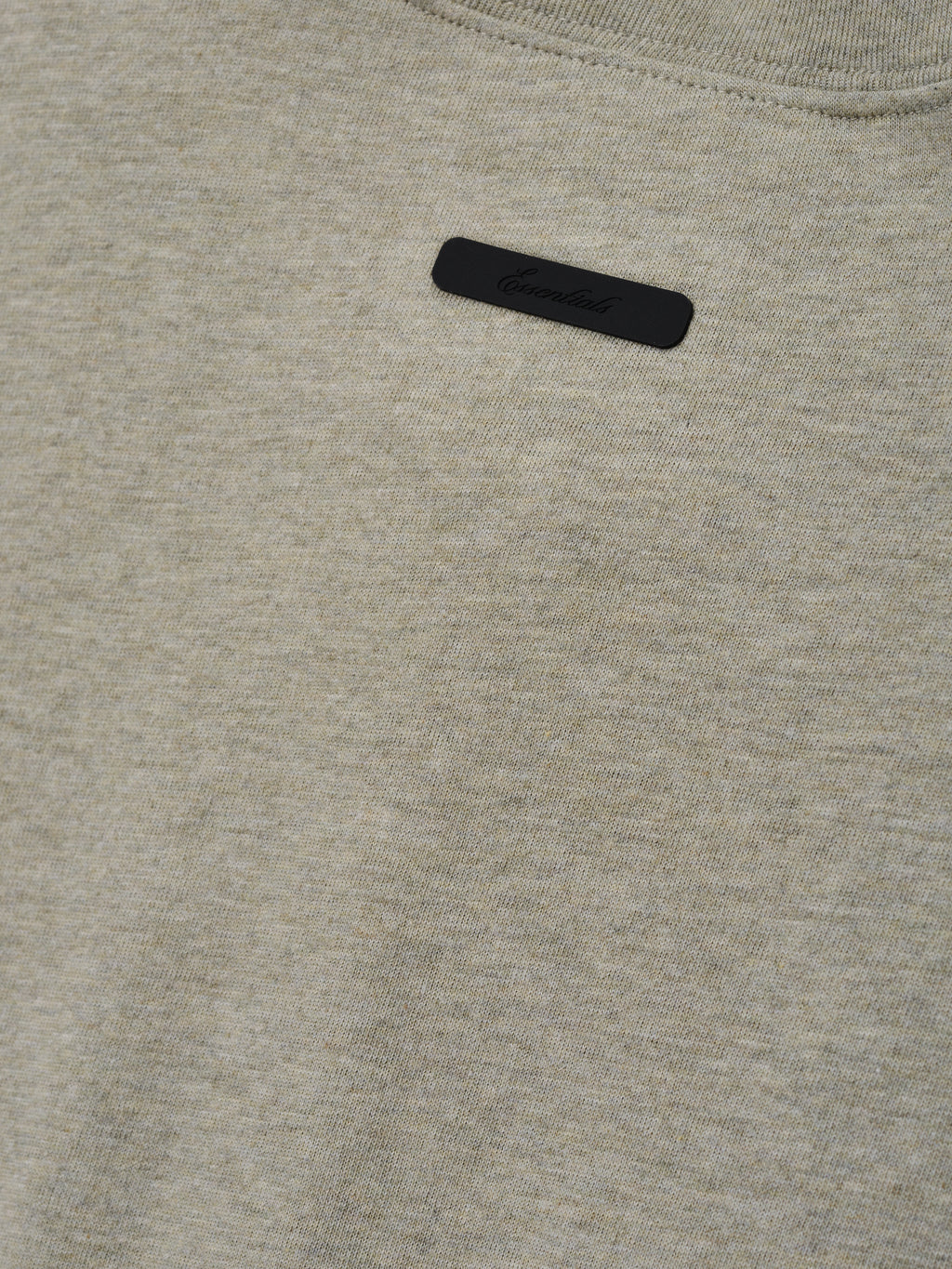 Kids Tri-Blend Essential Tee in a muted beige heather fabric featuring a small black rectangular label with subtle embossed branding near the neckline for a clean, modern look.