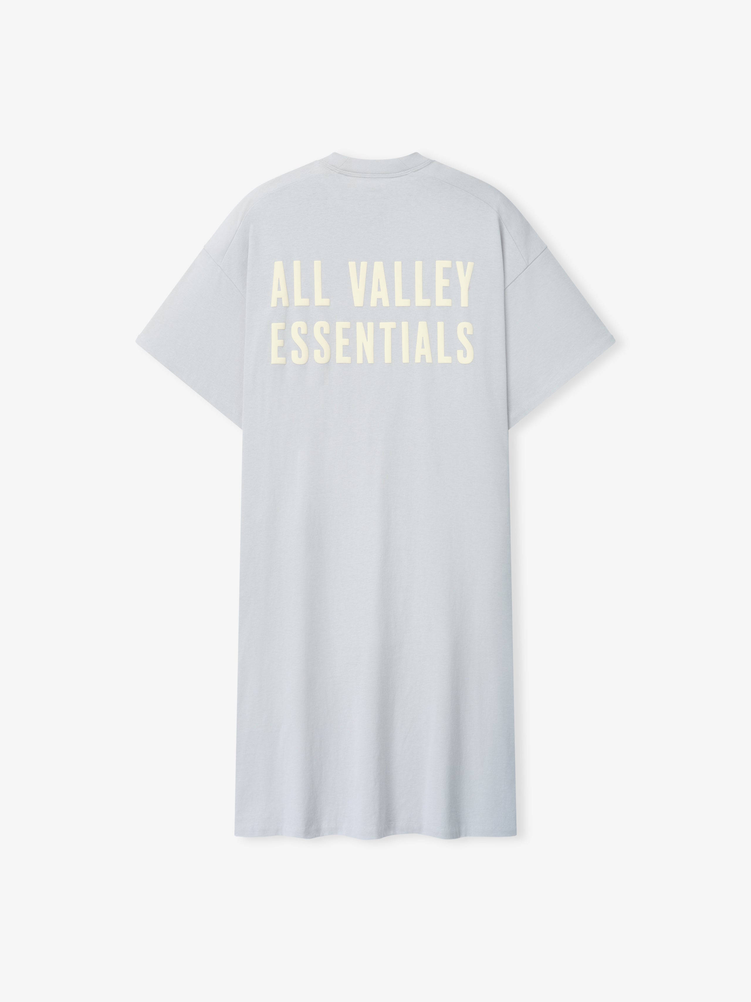 Womens Long TShirt Dress in soft light gray with a relaxed fit, short sleeves, and large cream-colored "ALL VALLEY ESSENTIALS" text printed across the upper back.