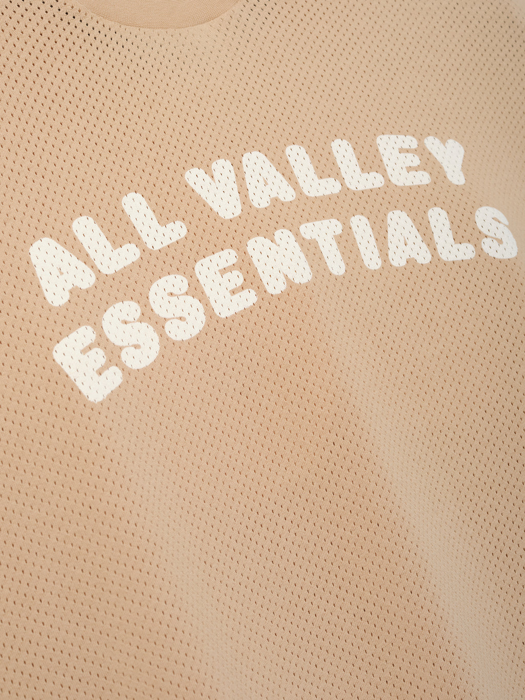 Womens Sport Mesh Merch Tee in warm ginger featuring breathable mesh fabric with bold white "ALL VALLEY ESSENTIALS" text printed across the chest for a sporty casual top.