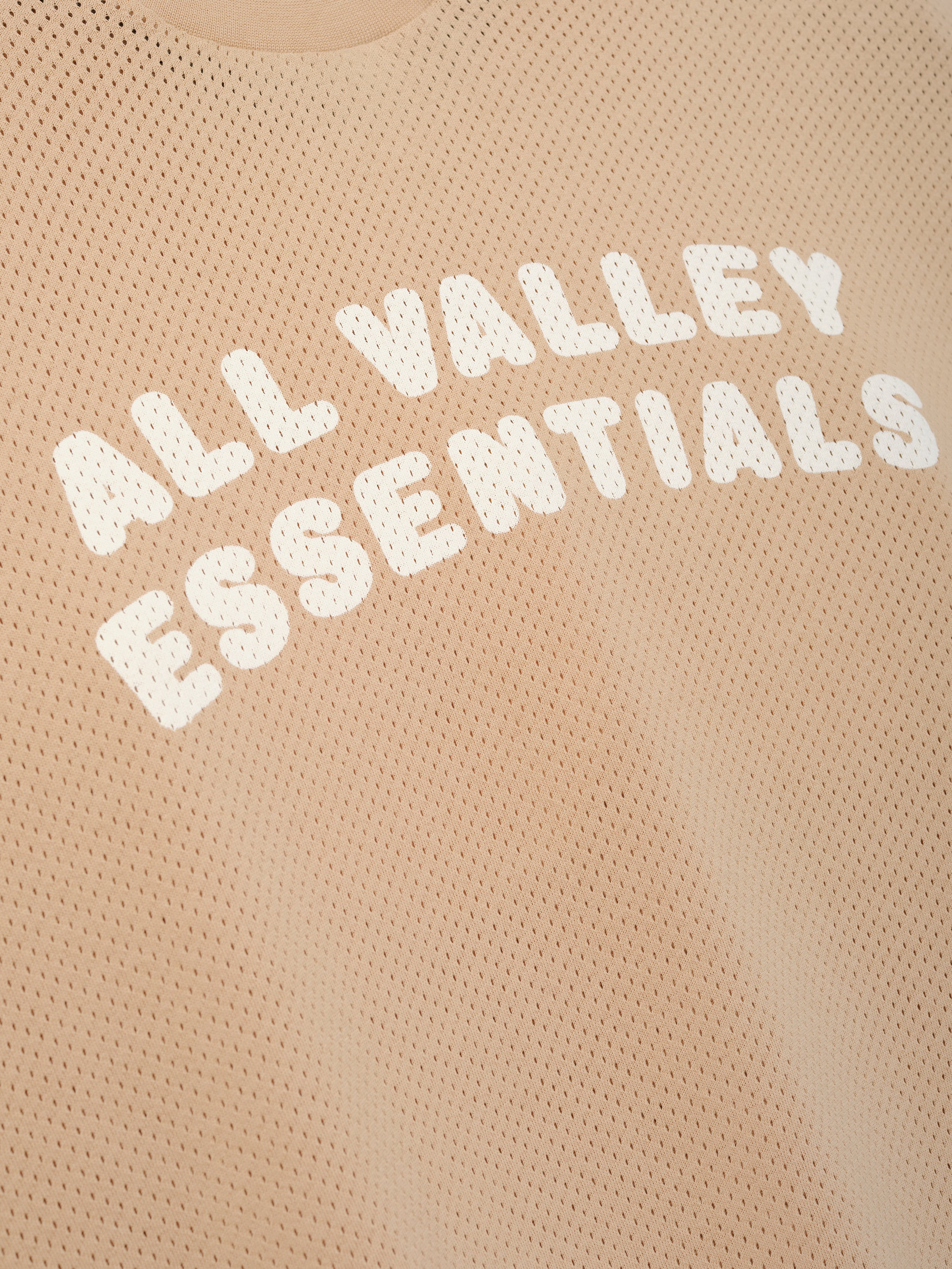 Womens Sport Mesh Merch Tee in warm ginger featuring breathable mesh fabric with bold white "ALL VALLEY ESSENTIALS" text printed across the chest for a sporty casual top.