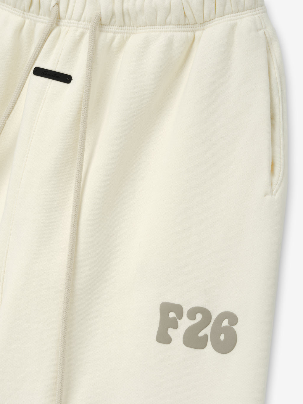 Womens Classic Fleece Sweatpant in a soft ivory shade featuring an elastic waistband with drawstrings, side pockets, and a raised F26 logo on the upper thigh for casual bottoms.