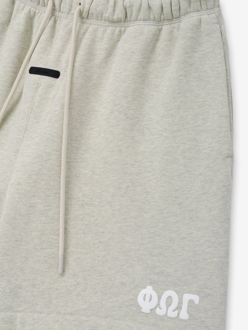 Classic Sweatshort in a soft light vanilla heather shade, featuring an elastic waistband with long drawstrings, side pockets, and a distinctive white stitched logo on the lower hem for casual bottoms.