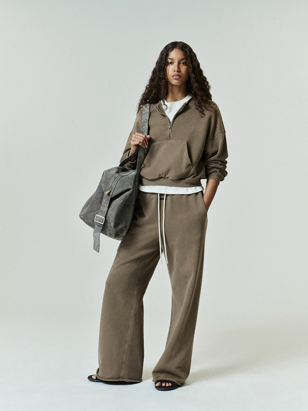 Womens French Terry Relaxed Half Zip in a muted olive tone, styled with wide-leg pants and a slouchy grey bag for an effortlessly cool and comfortable streetwear outfit.