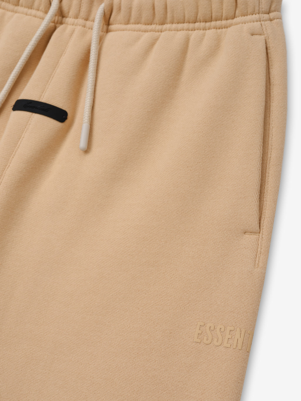 Kids Classic Fleece Sweatpant in a soft beige color, featuring an adjustable drawstring waistband, side pockets, and subtle embossed branding for comfortable and stylish kids bottoms.