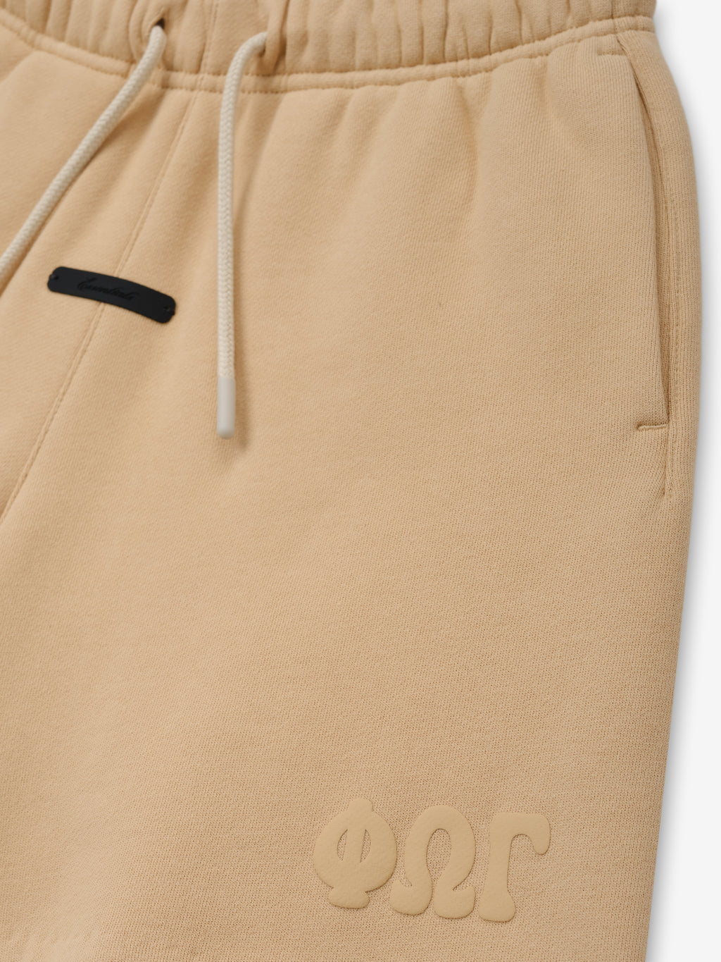 Kids Classic Sweatshort in a light beige color, featuring a soft elastic waistband with drawstrings, side pockets, and subtle embossed branding for comfortable kids bottoms.