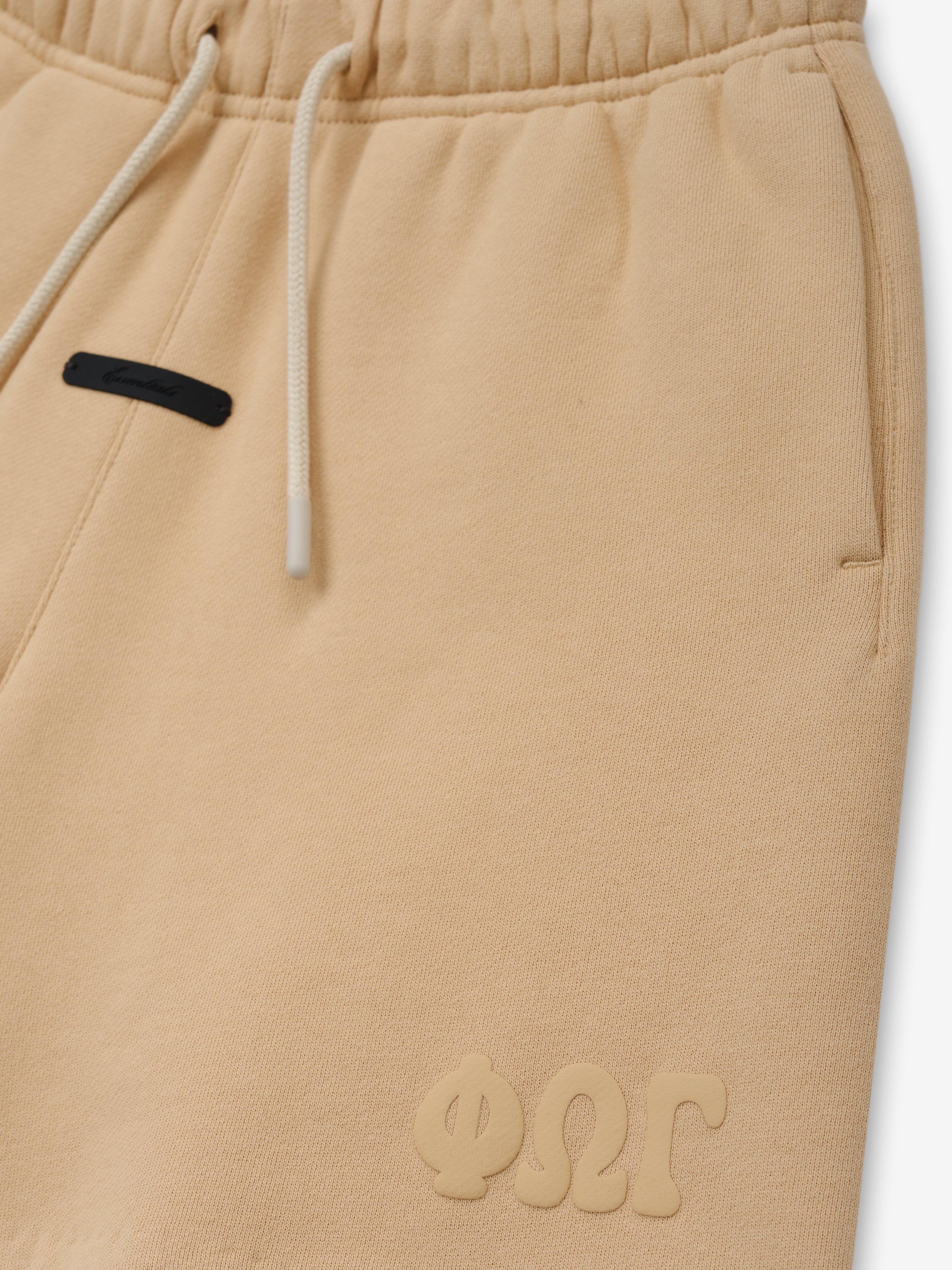 Kids Classic Sweatshort in a light beige color, featuring a soft elastic waistband with drawstrings, side pockets, and subtle embossed branding for comfortable kids bottoms.