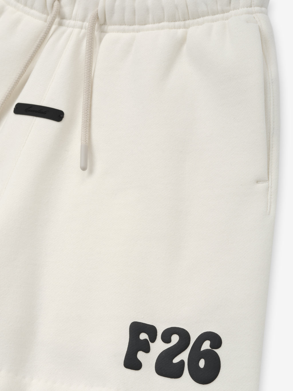 Kids Classic Sweatshort in a creamy ivory tone, featuring a soft elastic waistband with drawstrings, side pockets, and bold black "F26" printed detail for stylish kids bottoms.