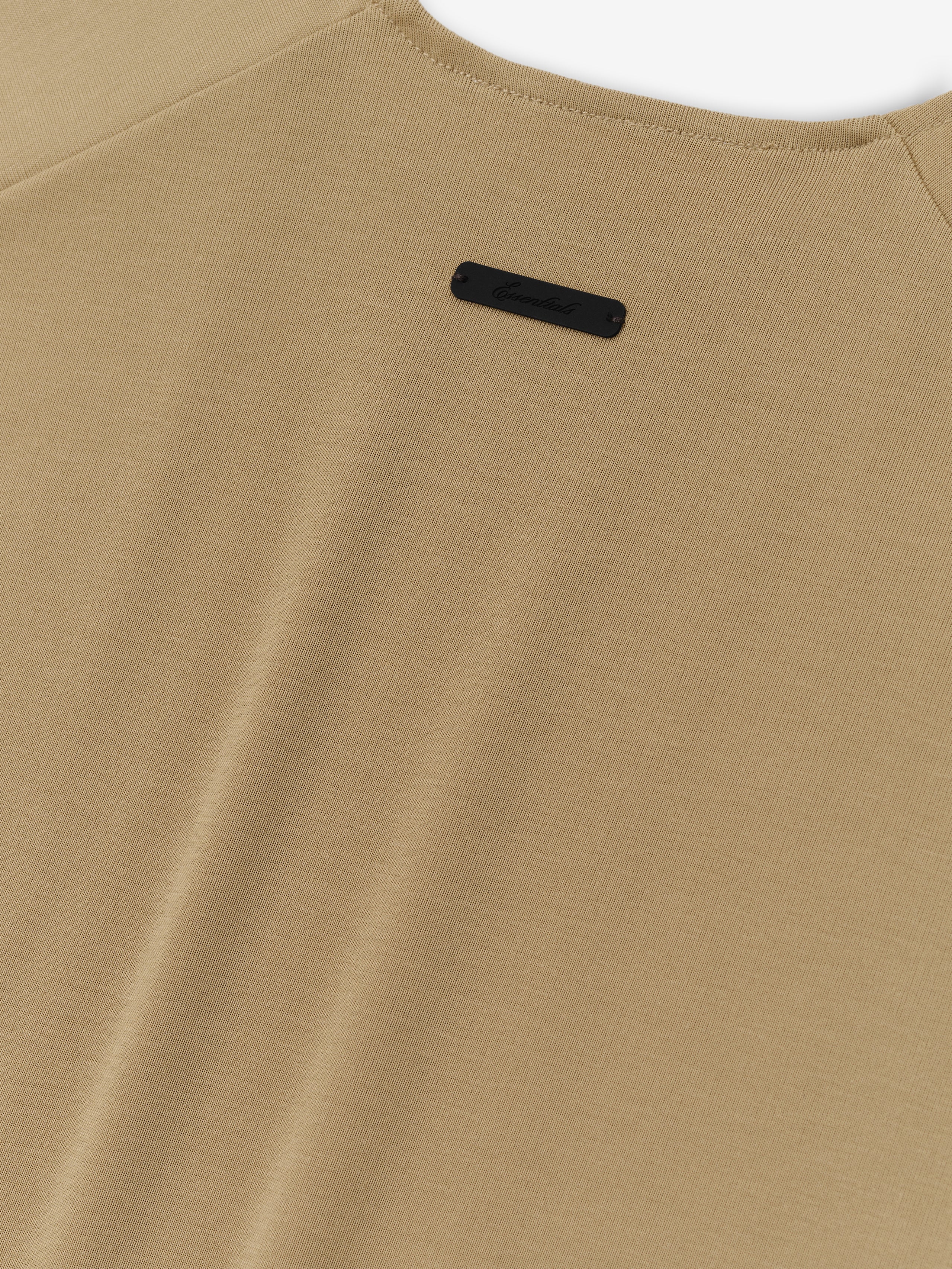 Womens Soft Rib Fitted Tank in a muted dune beige, featuring a smooth ribbed fabric with a minimalist back neckline and a small black logo patch for subtle branding.
