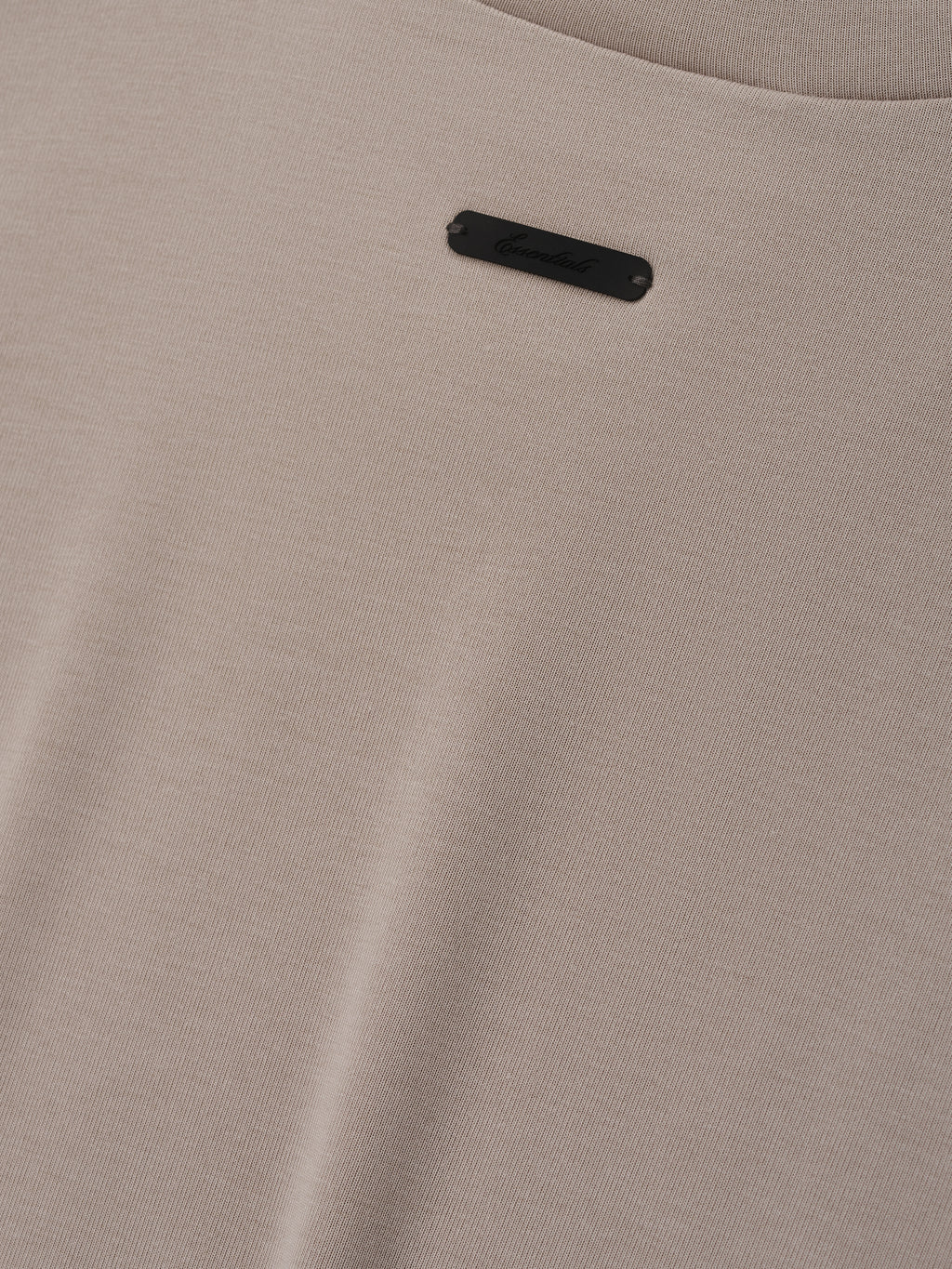 Soft Rib Fitted T-Shirt in a warm neutral beige tone, showcasing a finely ribbed texture with a small discreet black logo plaque for a subtle, refined detail on a minimalist top.