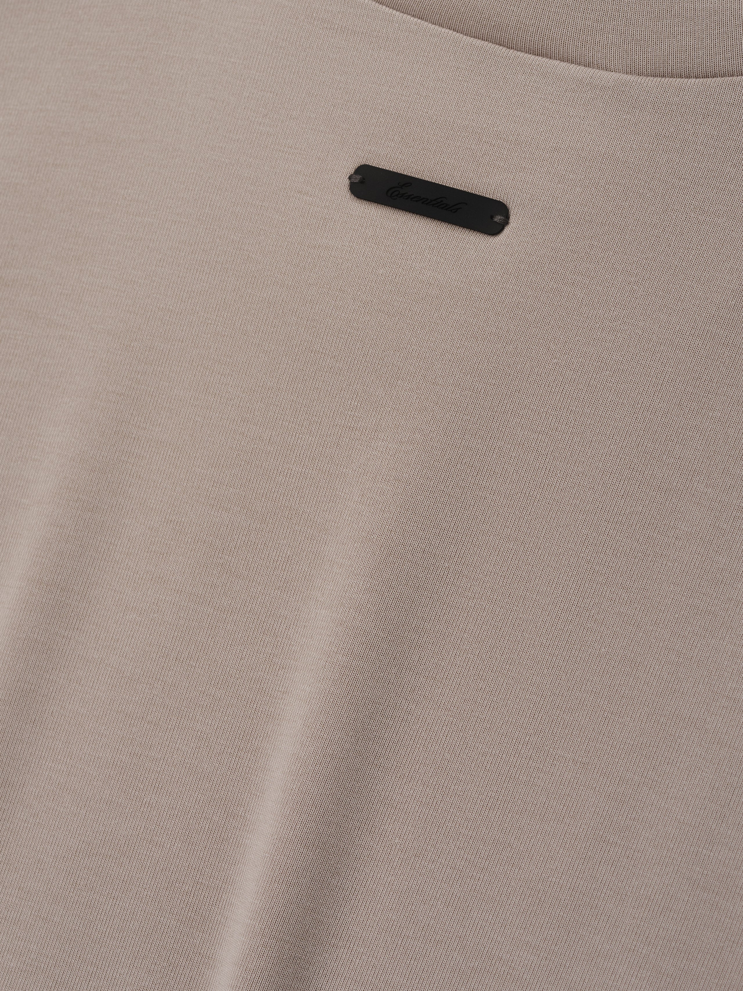Soft Rib Fitted T-Shirt in a warm neutral beige tone, showcasing a finely ribbed texture with a small discreet black logo plaque for a subtle, refined detail on a minimalist top.