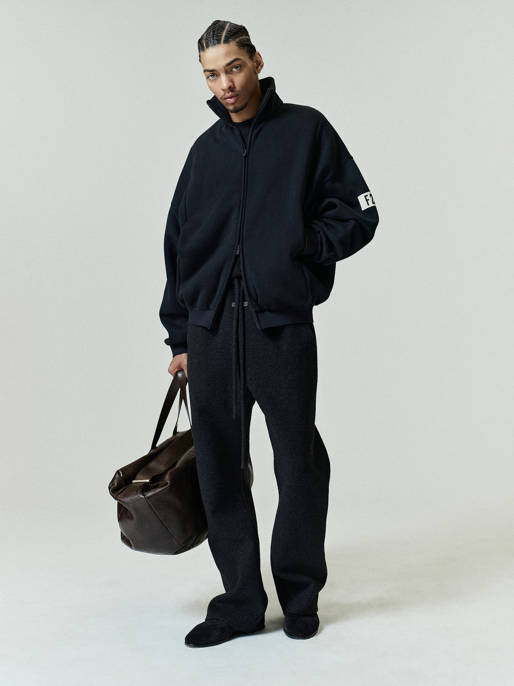 Model wearing a vintage black Track Jacket with a relaxed fit, featuring a high collar, full zip closure, and subtle sleeve branding, styled as casual outerwear.
