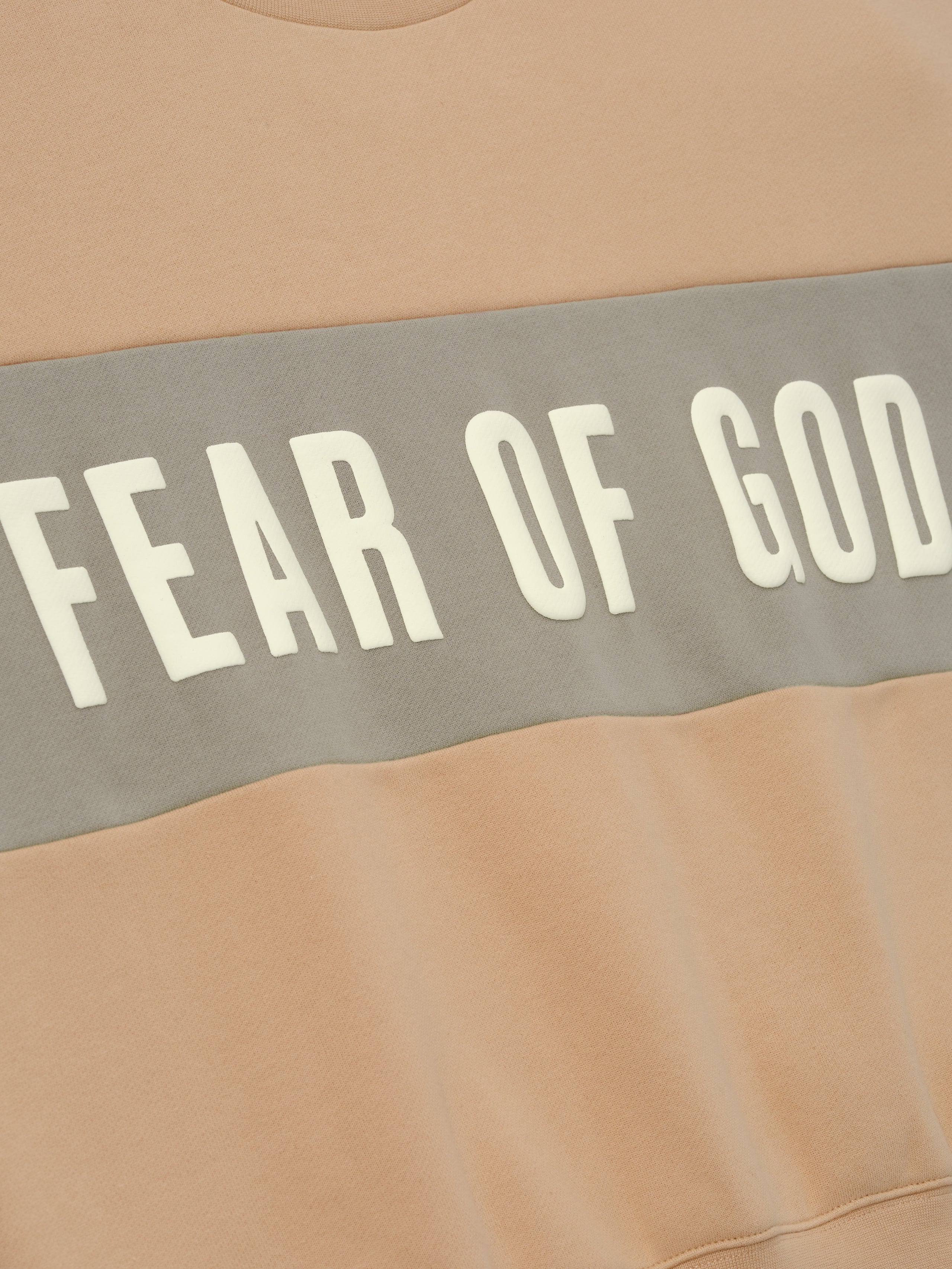 Womens Paneled Classic Sweatshirt in a warm beige shade with a contrasting muted gray panel across the chest featuring bold Fear of God lettering, designed as comfortable outerwear.