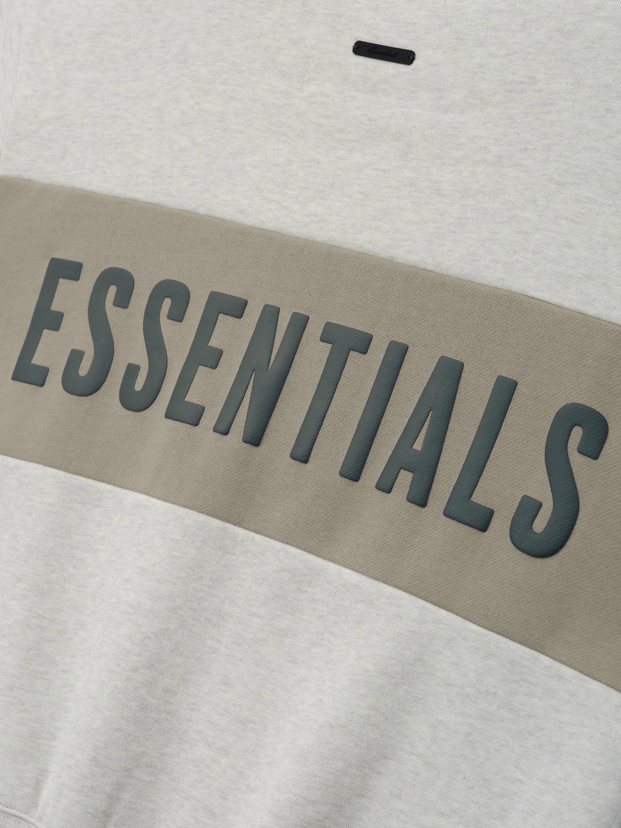 Womens Paneled Classic Sweatshirt in a soft vanilla heather tone with a wide muted taupe panel across the chest showcasing raised dark gray ESSENTIALS lettering, casual outerwear top.