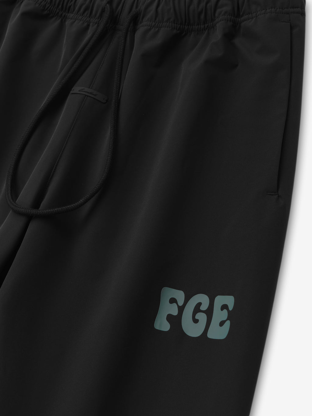 Womens Storm Pant in black featuring a relaxed fit with an elastic waistband and drawstring closure, accented by a subtle FGE logo on the thigh, designed as comfortable bottoms.
