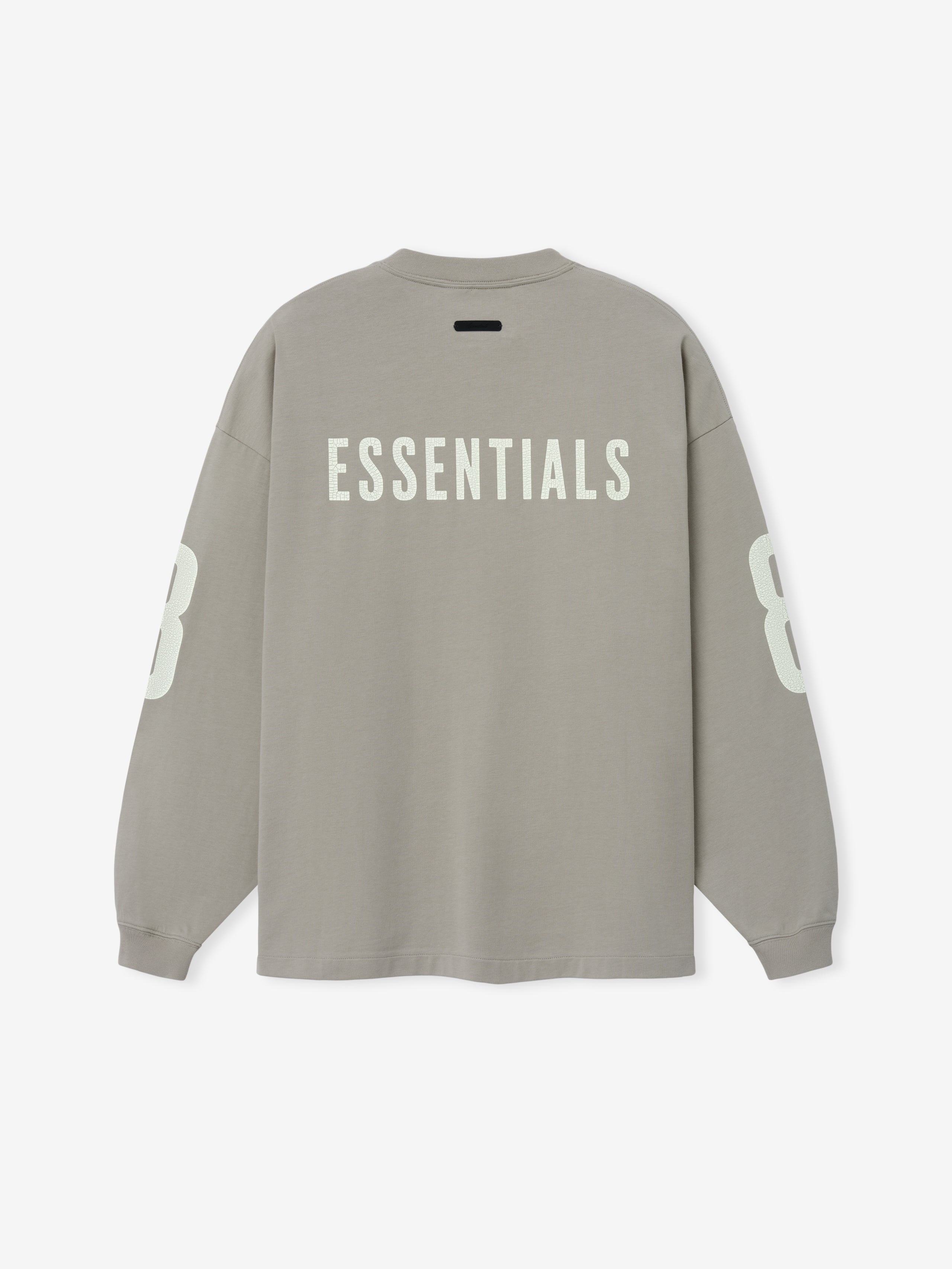 Merch Long Sleeve Tee in muted taupe showcasing bold "ESSENTIALS" text across the upper back and large contrasting numbers on each sleeve for a streetwear-inspired look.